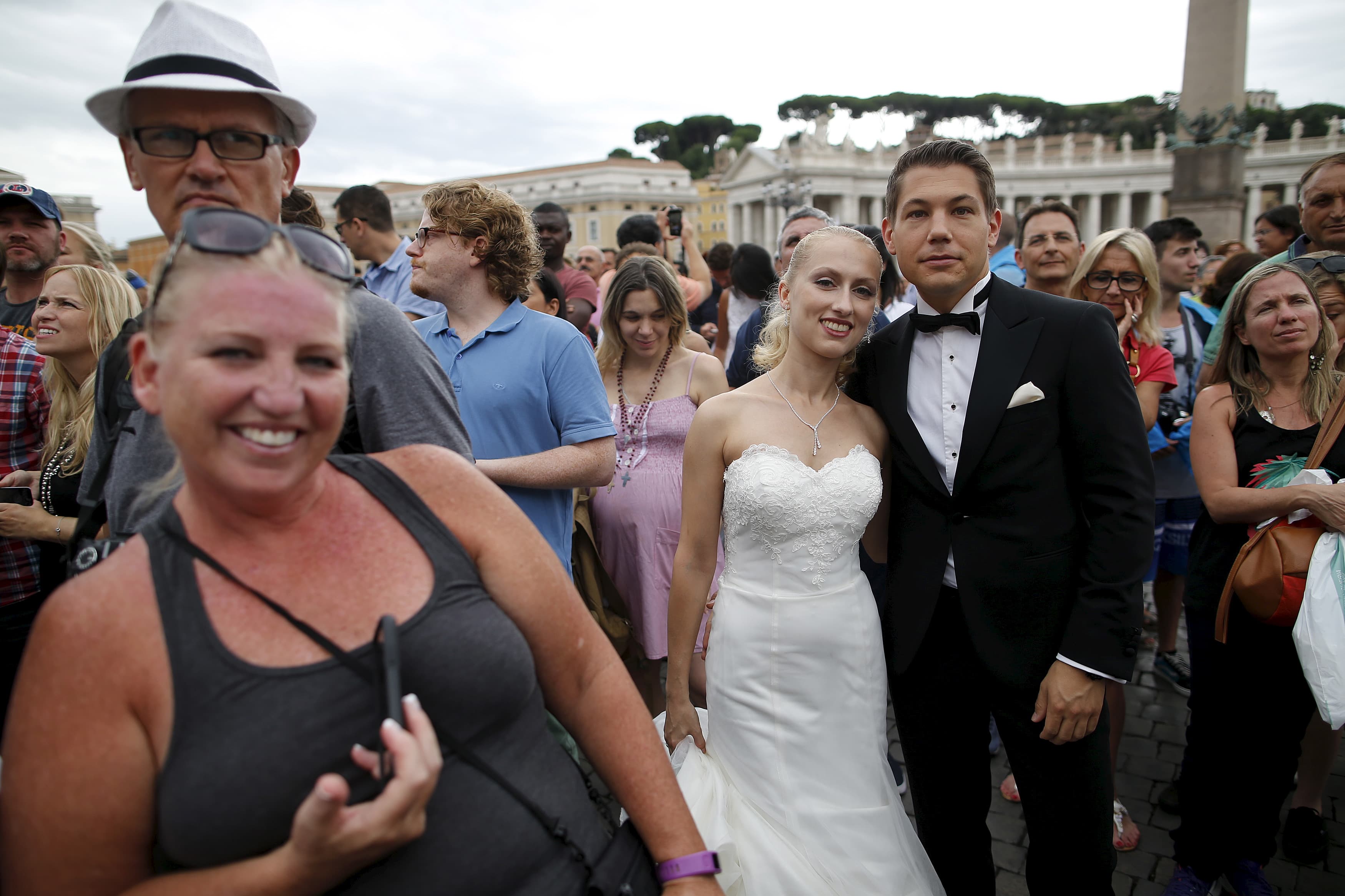 A newly wed couple attends as Pope Francis leads his Sunday Angelus prayer in Saint Peter's square at the Vatican, August 16, 2015.
