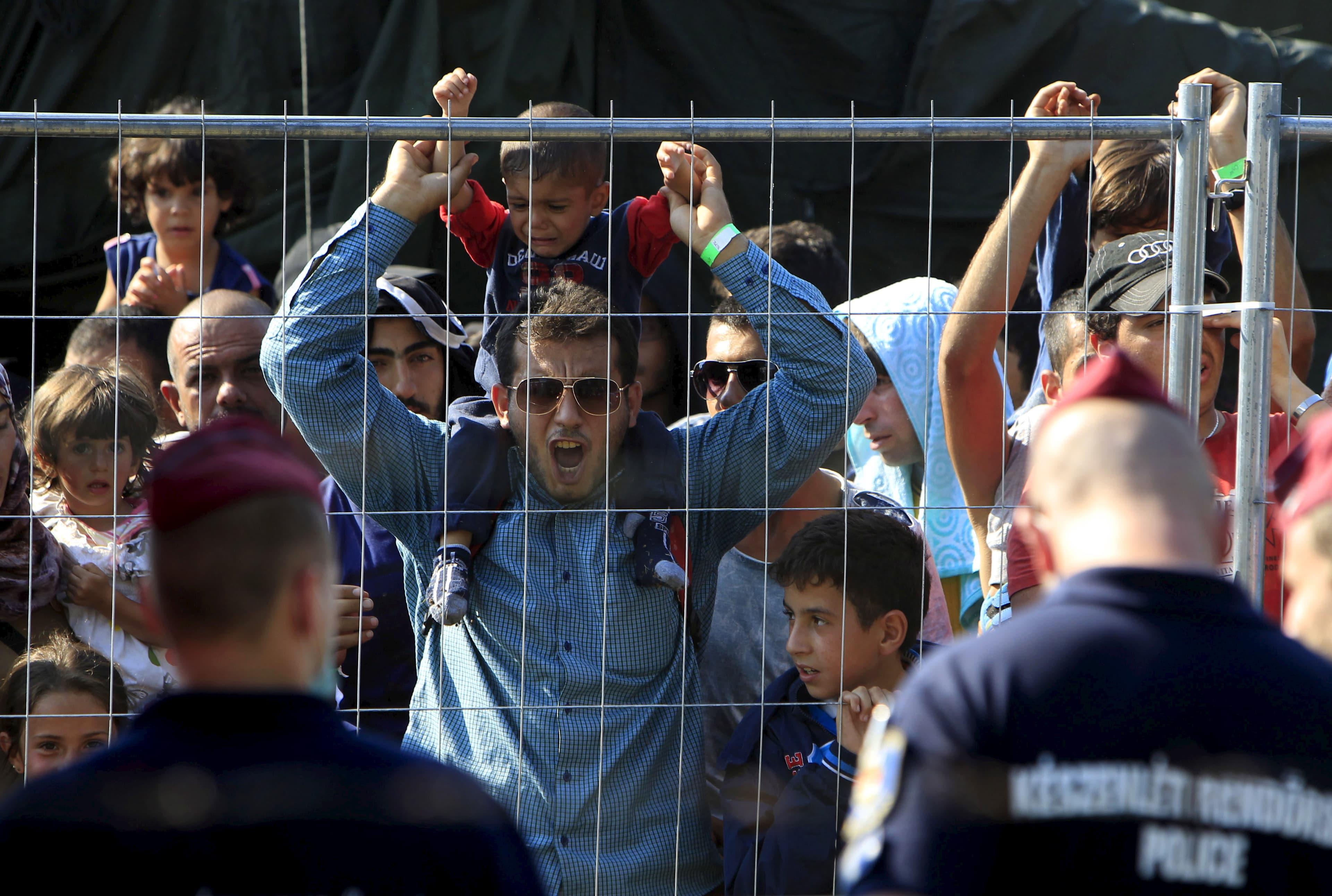 Syrian migrants shout slogans at a refugee camp in Roszke, Hungary, August 28, 2015.