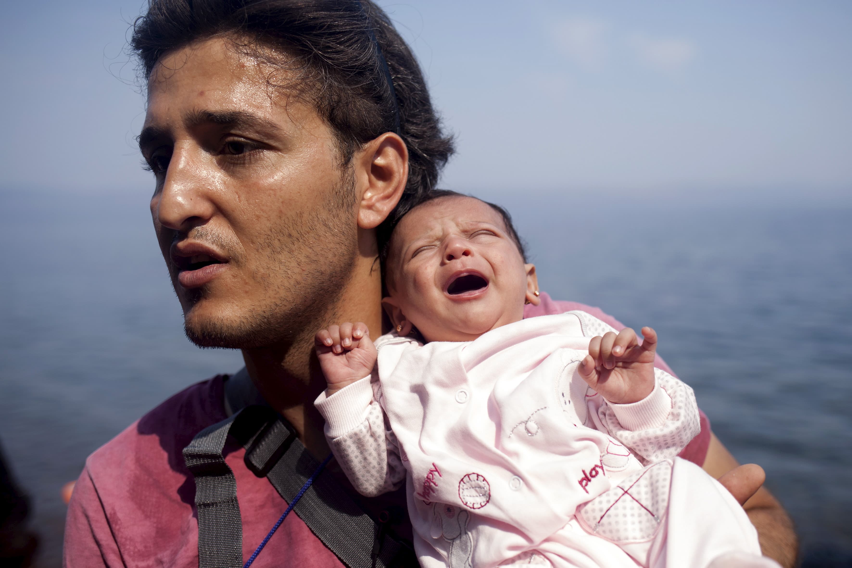 A Syrian refugee from Aleppo holds his one month old daughter moments after arriving on a dinghy on the Greek island of Lesbos