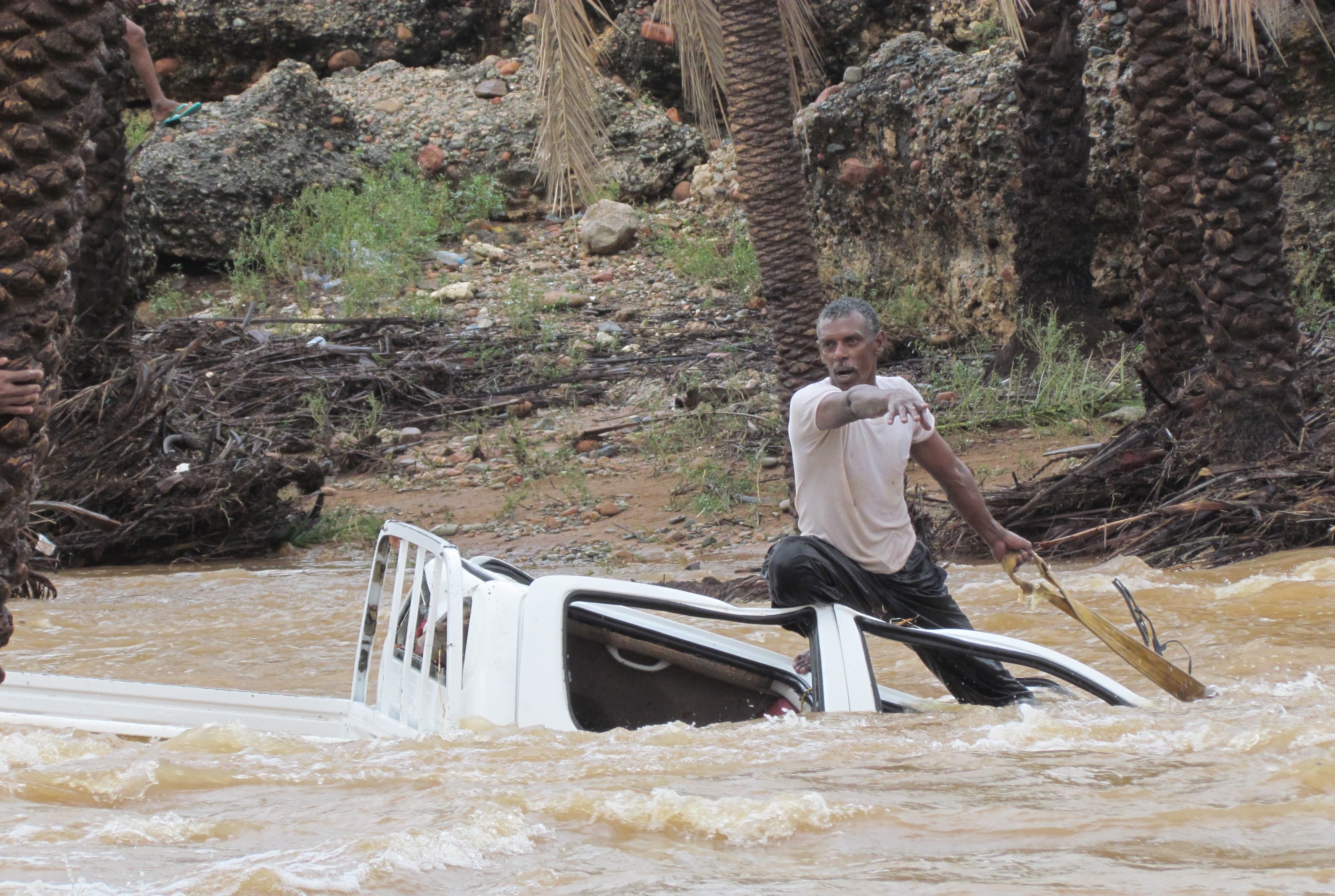 A man gestures as he tries to save a vehicle swept away by flood waters in Yemen's island of Socotra November 2, 2015.
