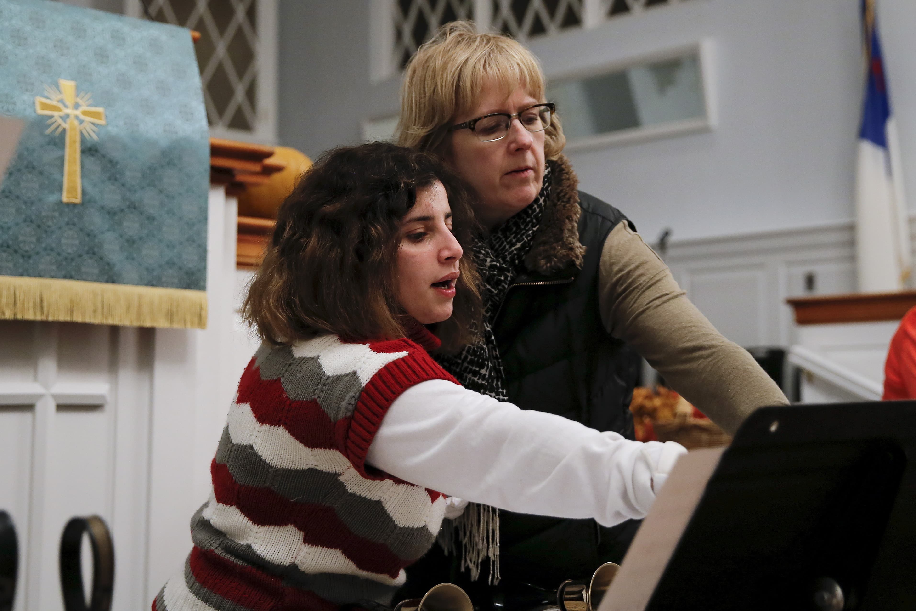A woman and young girl in a church look at sheet music
