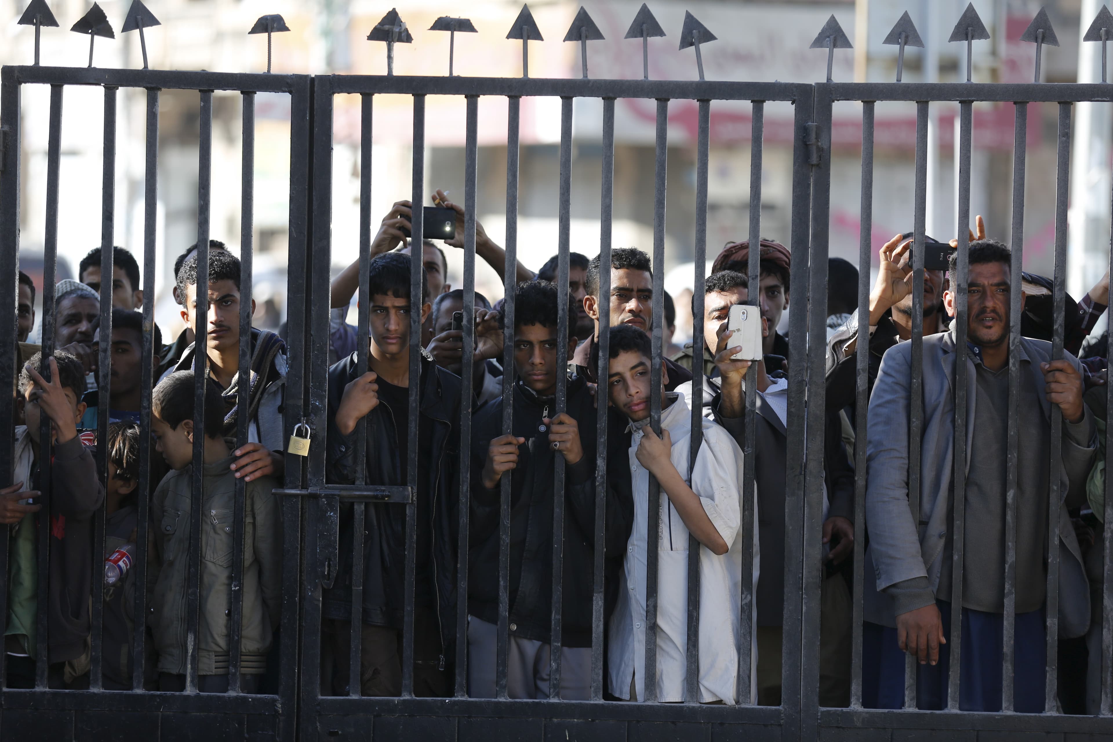 People look through a gate bars in Sanaa