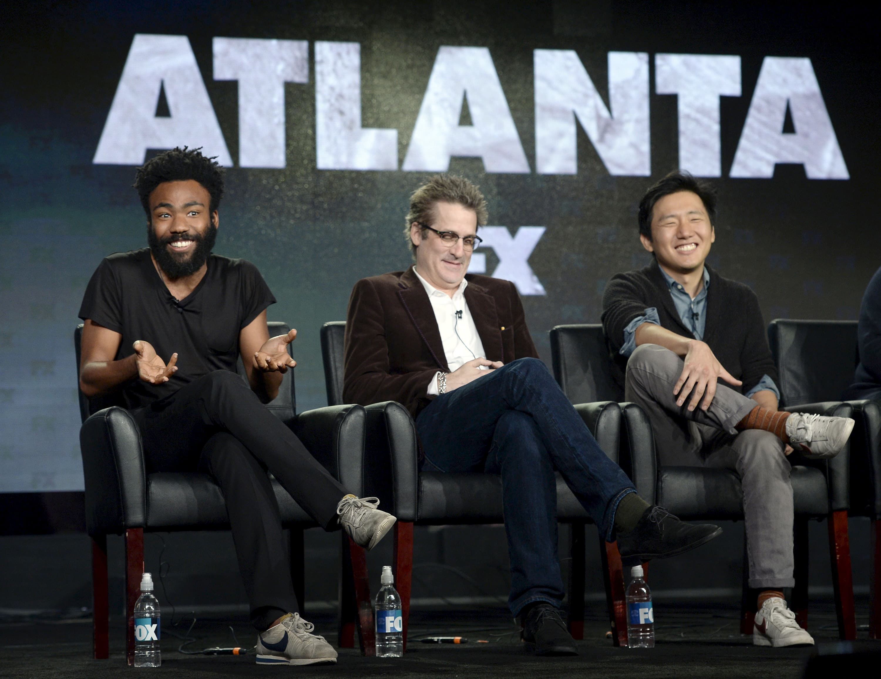 Three men on seats on stage, with word ATLANTA behind them