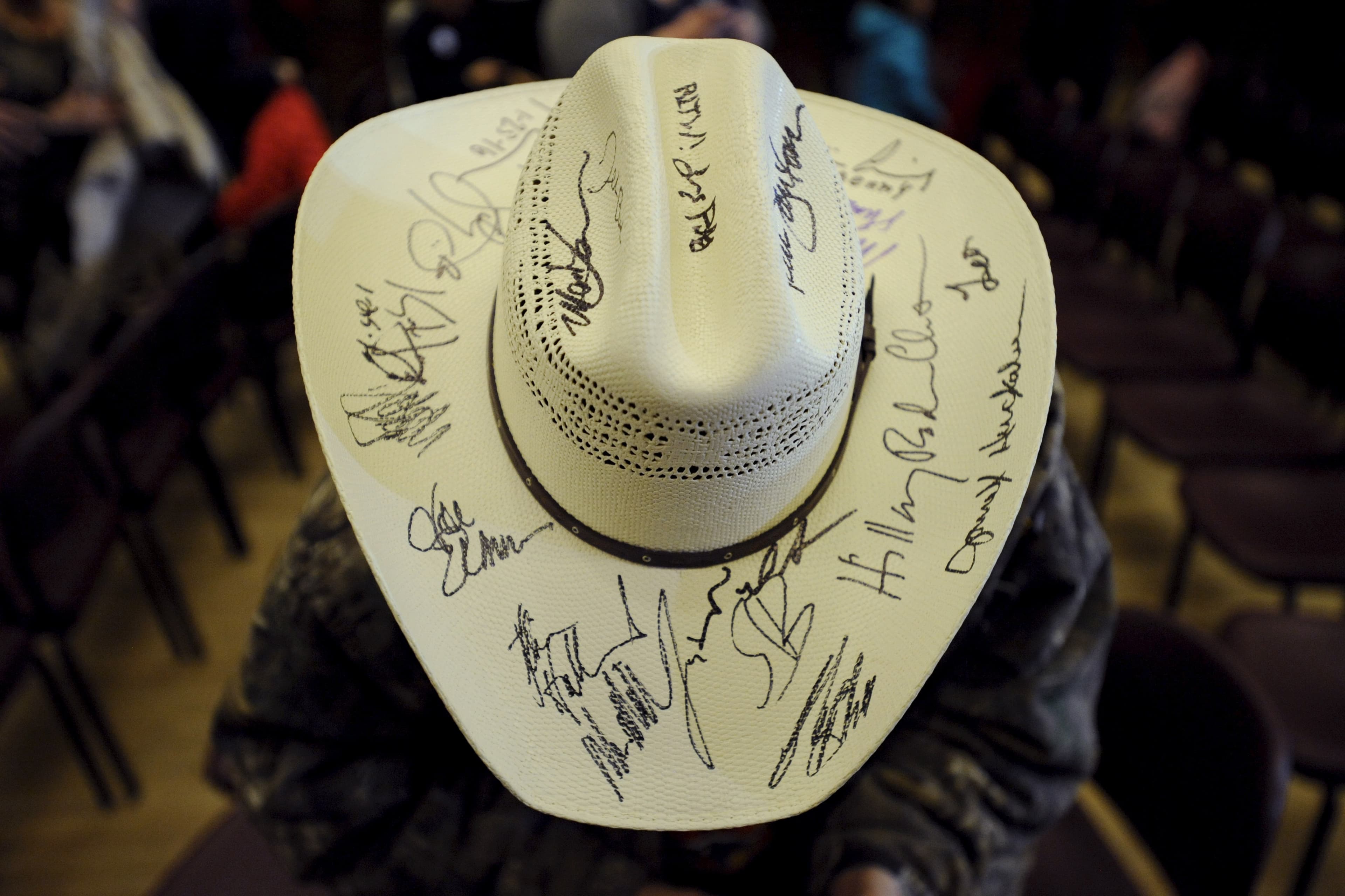 A voter shows off a hat covered in signatures from presidential candidates after a rally at Iowa State University in Ames, Iowa