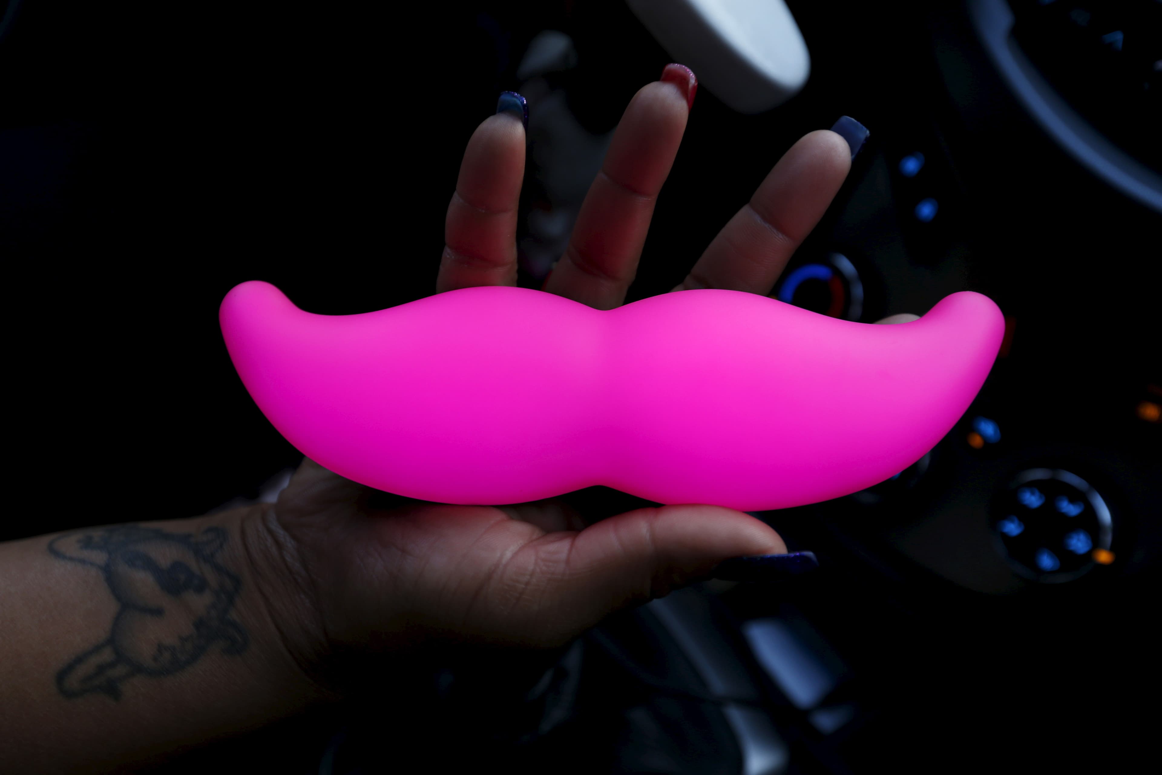 A woman holds a glow in the dark mustache