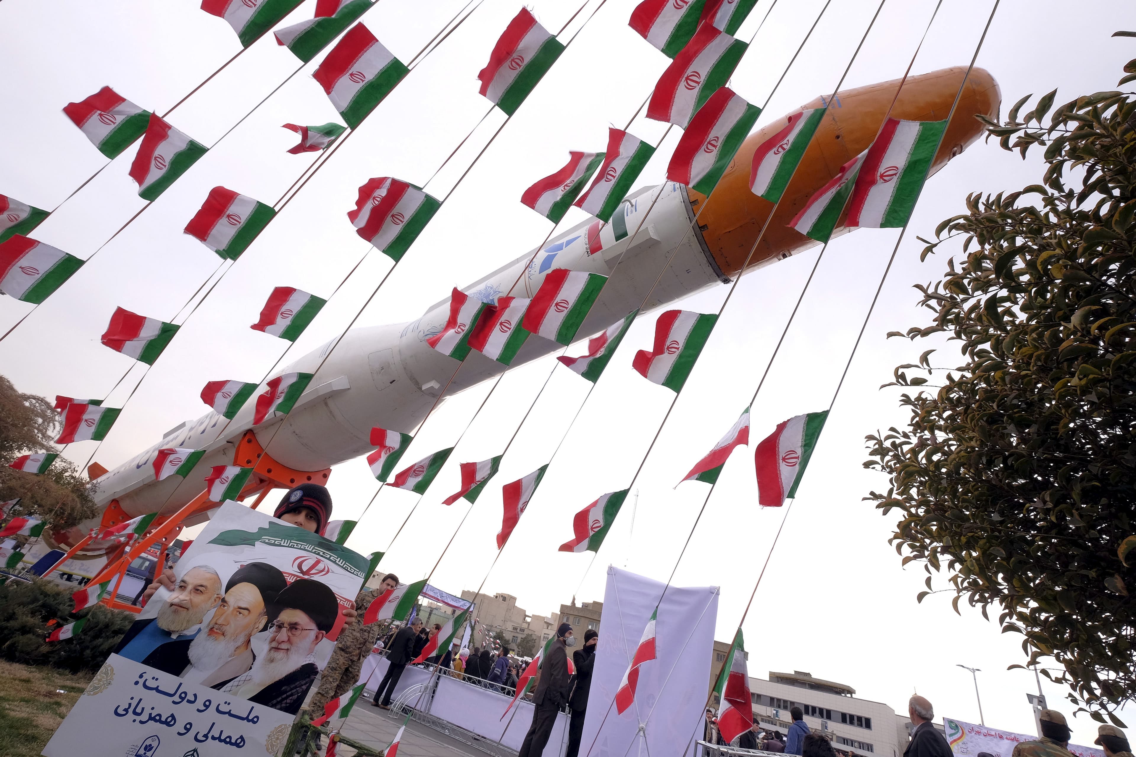 A boy holding a placard poses for camera in front of a model of Simorgh satellite-carrier rocket during a ceremony marking the 37th anniversary of the Islamic Revolution, in Tehran on February 11, 2016.