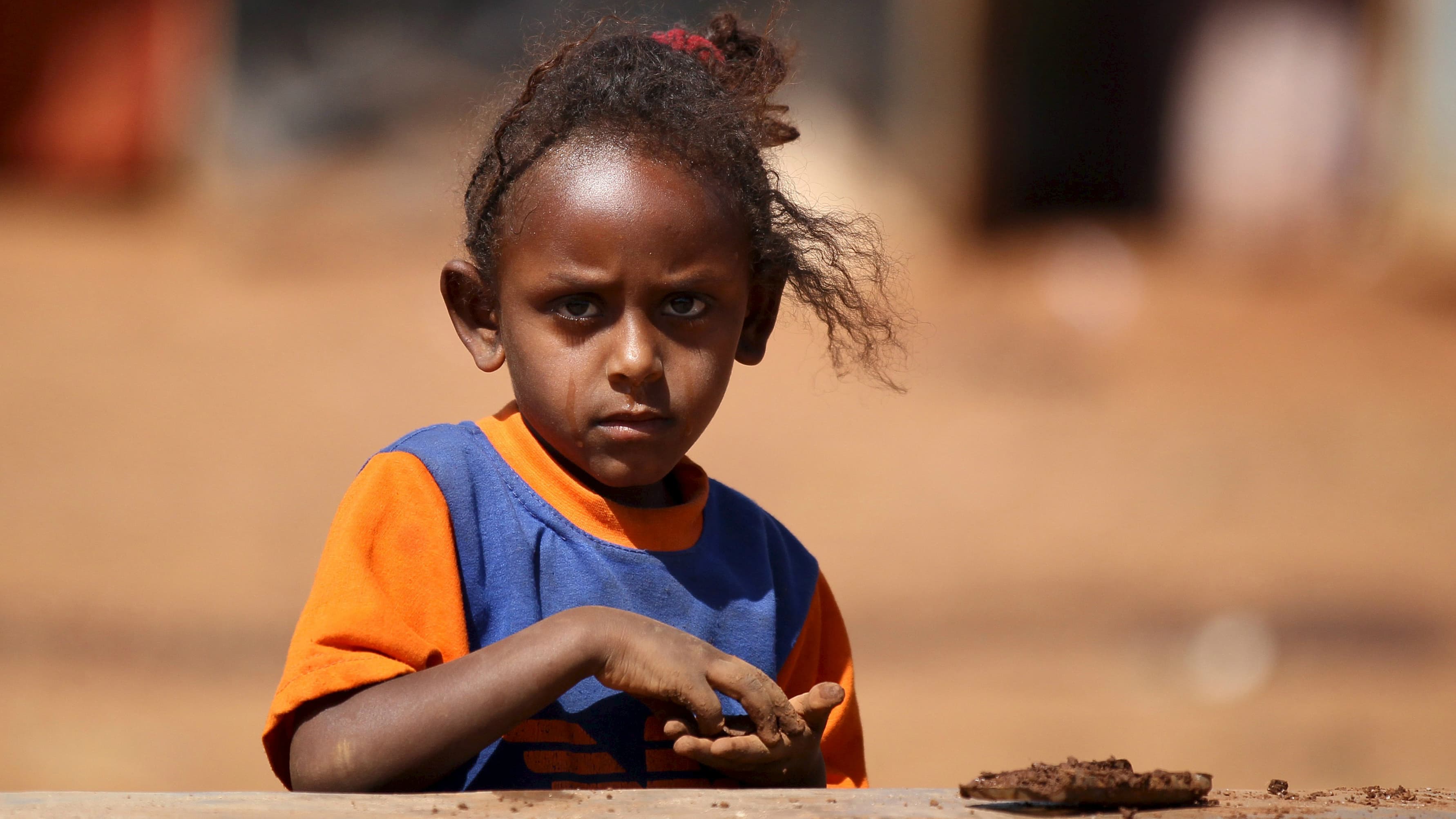 An Eritrean refugee girl plays with clay in front of a shelter in Mai-Aini refugee camp near in the Tigray region of Ethiopia, Feb. 10, 2016.
