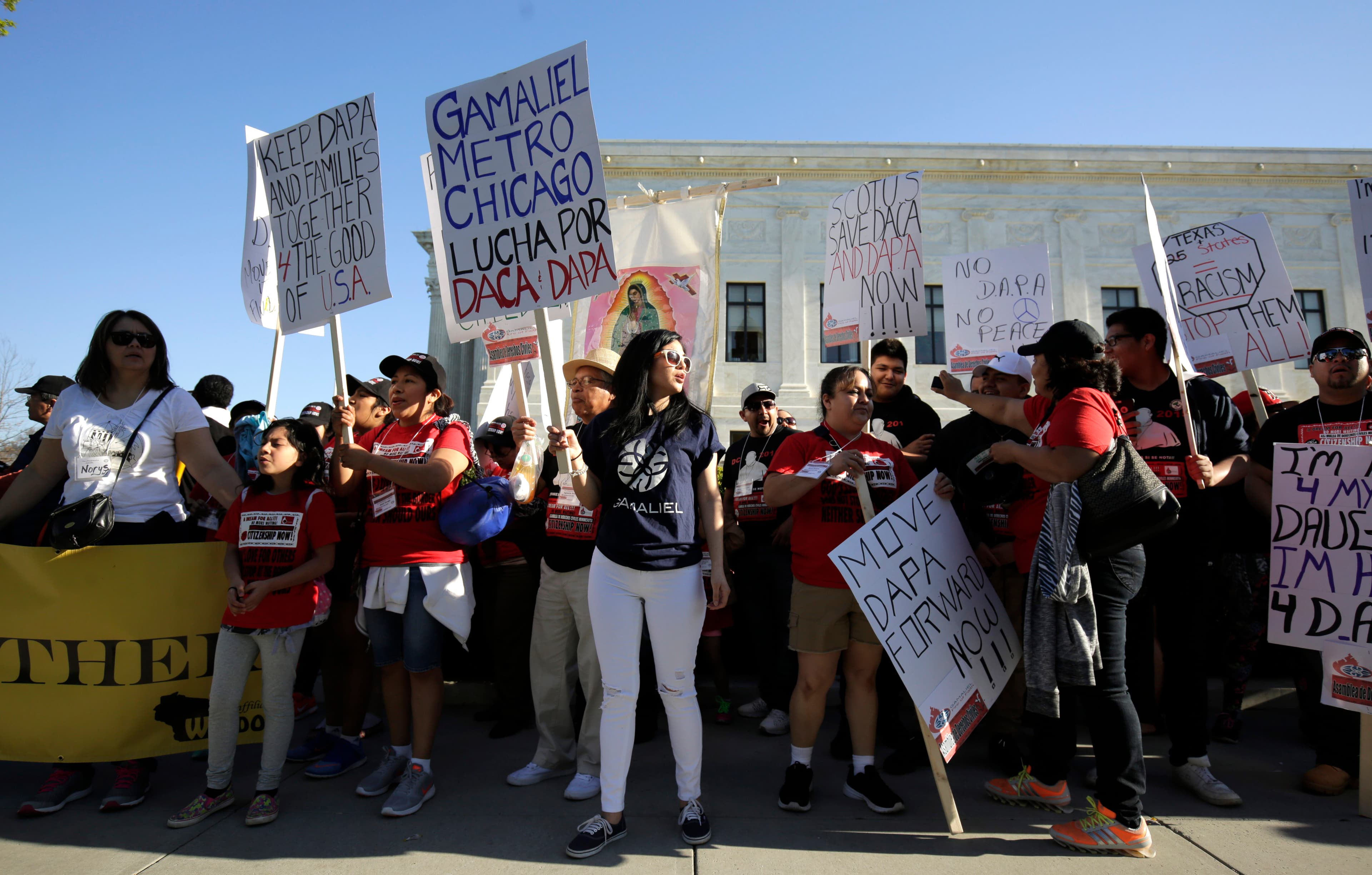 Demonstrators hold signs asking the Supreme Court to allow DAPA to move forward