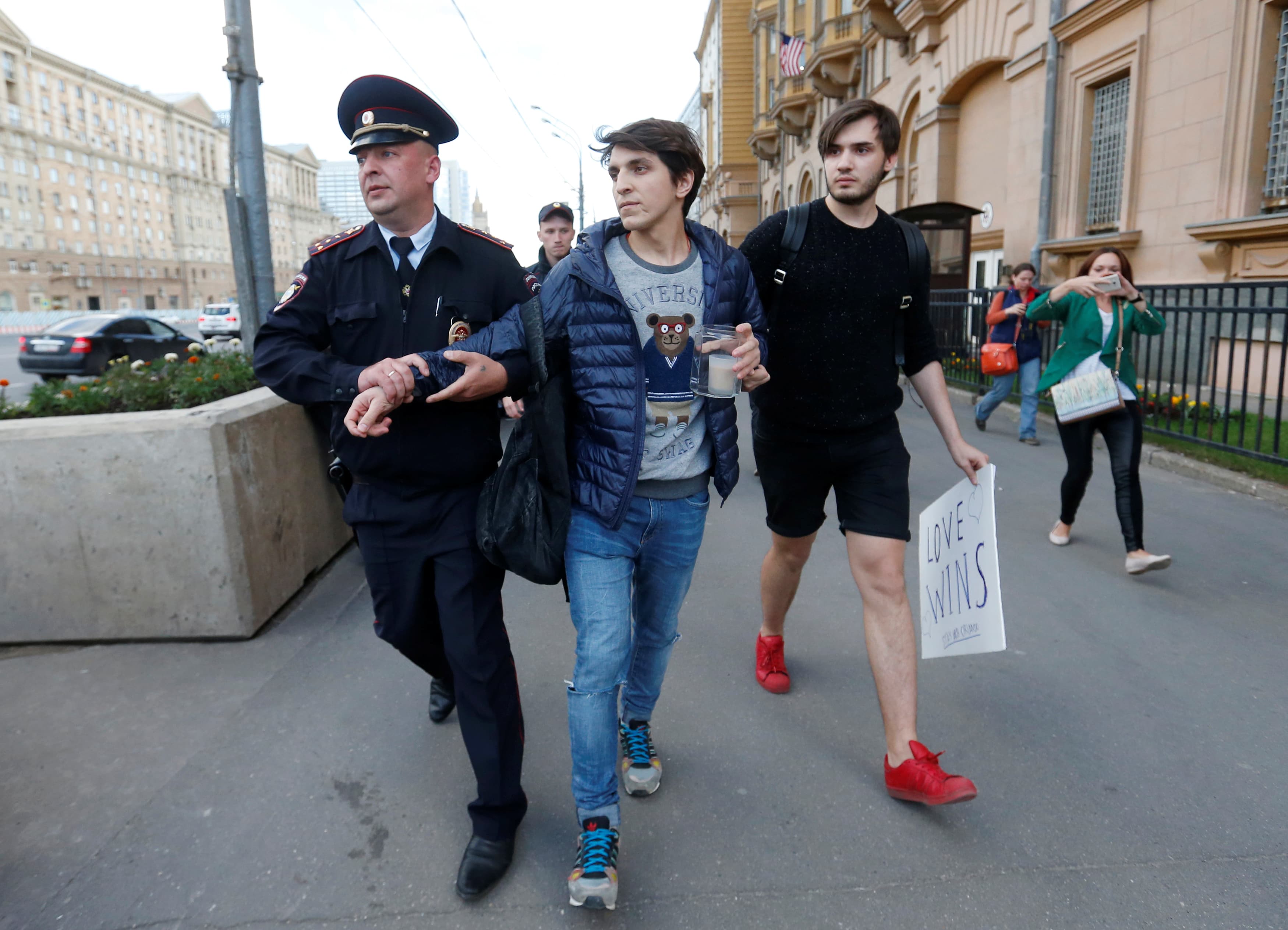 A Russian police officer detains a man as he intended to place a candle and a placard for the victims of the shooting at a gay nightclub in Orlando in front of the U.S. Embassy in Moscow, Russia, June 13, 2016.