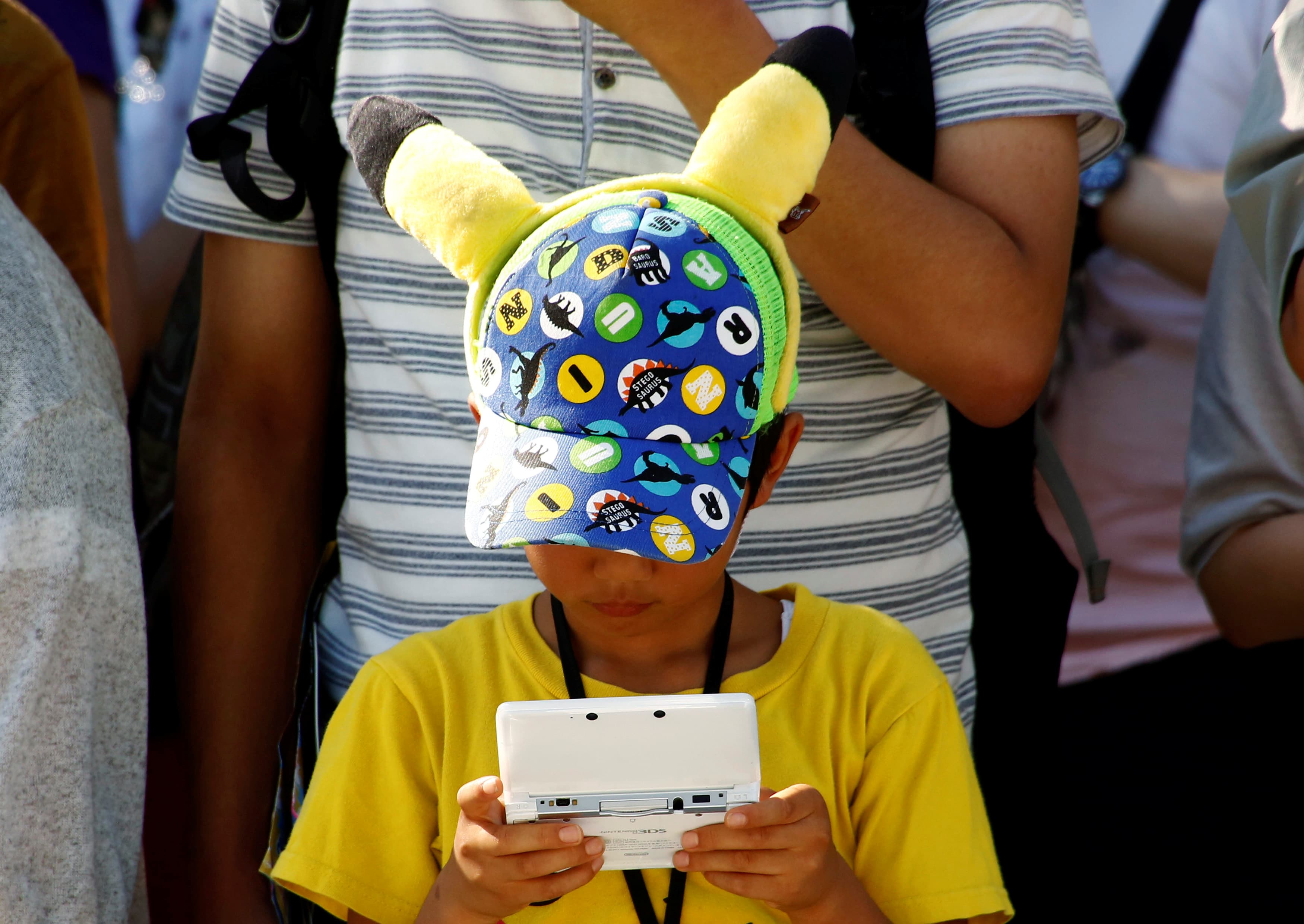 A boy in a Pikachu hat plays a Nintendo game console