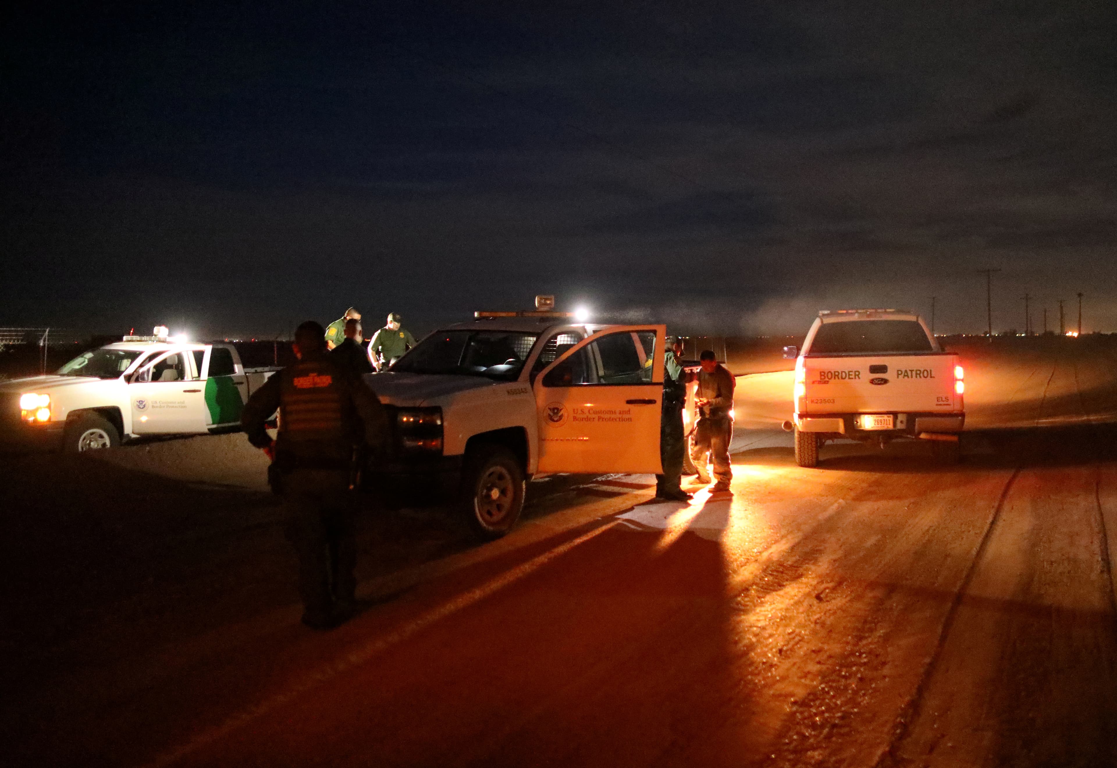 Night scene on street with law enforcement vehicles stopped, arresting man