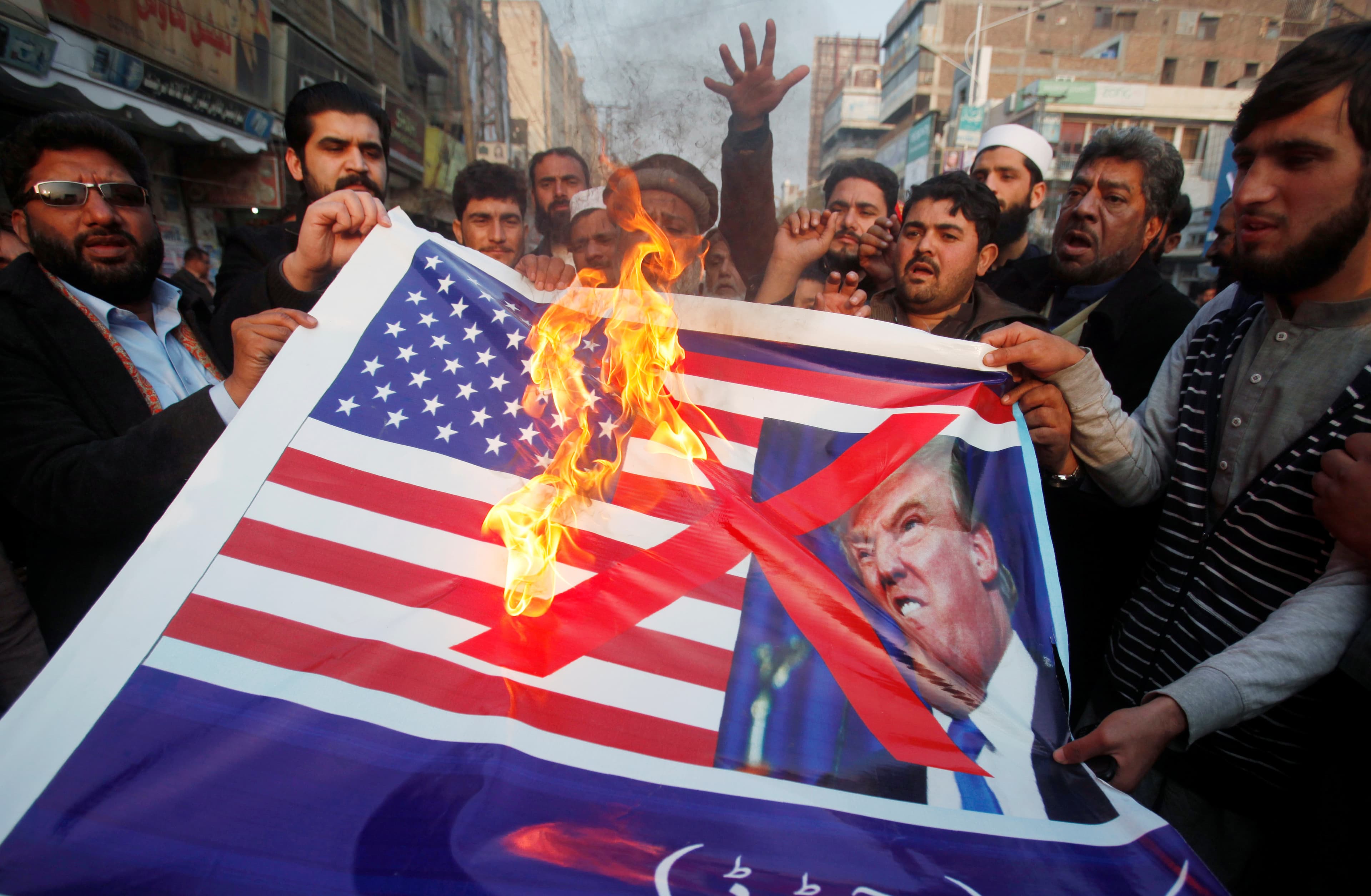 People burn a sign depicting a U.S. flag and a picture of U.S. President Donald Trump as they take part in an anti-U.S. rally in Peshawar, Pakistan, January 5, 2018.