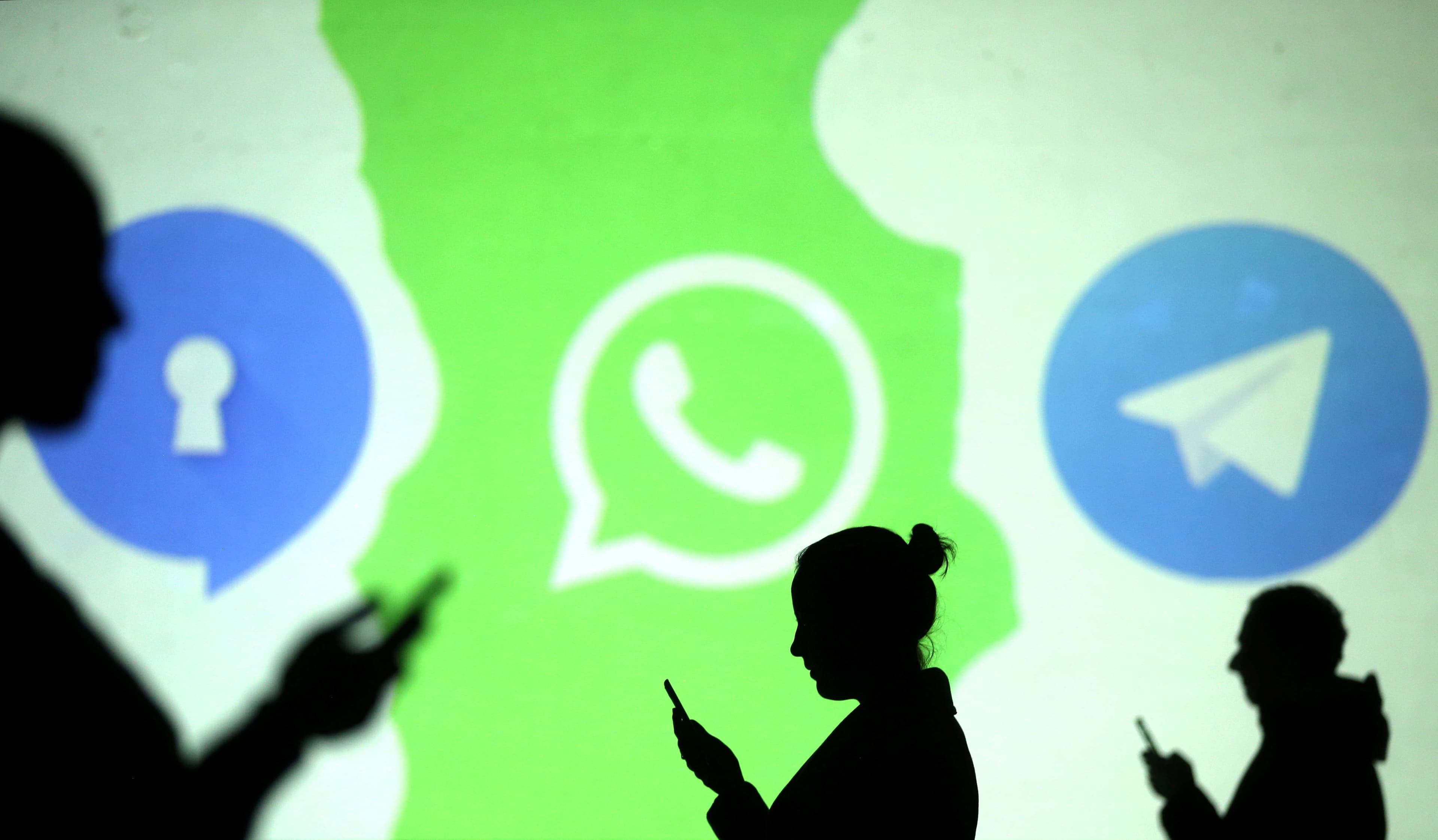 Silhouettes of mobile users are seen next to logos of social media apps Signal, Whatsapp and Telegram projected on a screen in this picture illustration taken March 28, 2018.