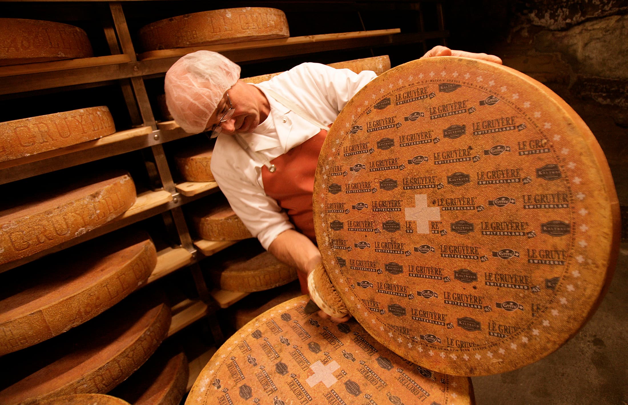 A Swiss cheesemaker inspects a large wheel of cave-aged Gruyere cheese. Such cheeses can be windows into the culture and geography of the places where they're made.