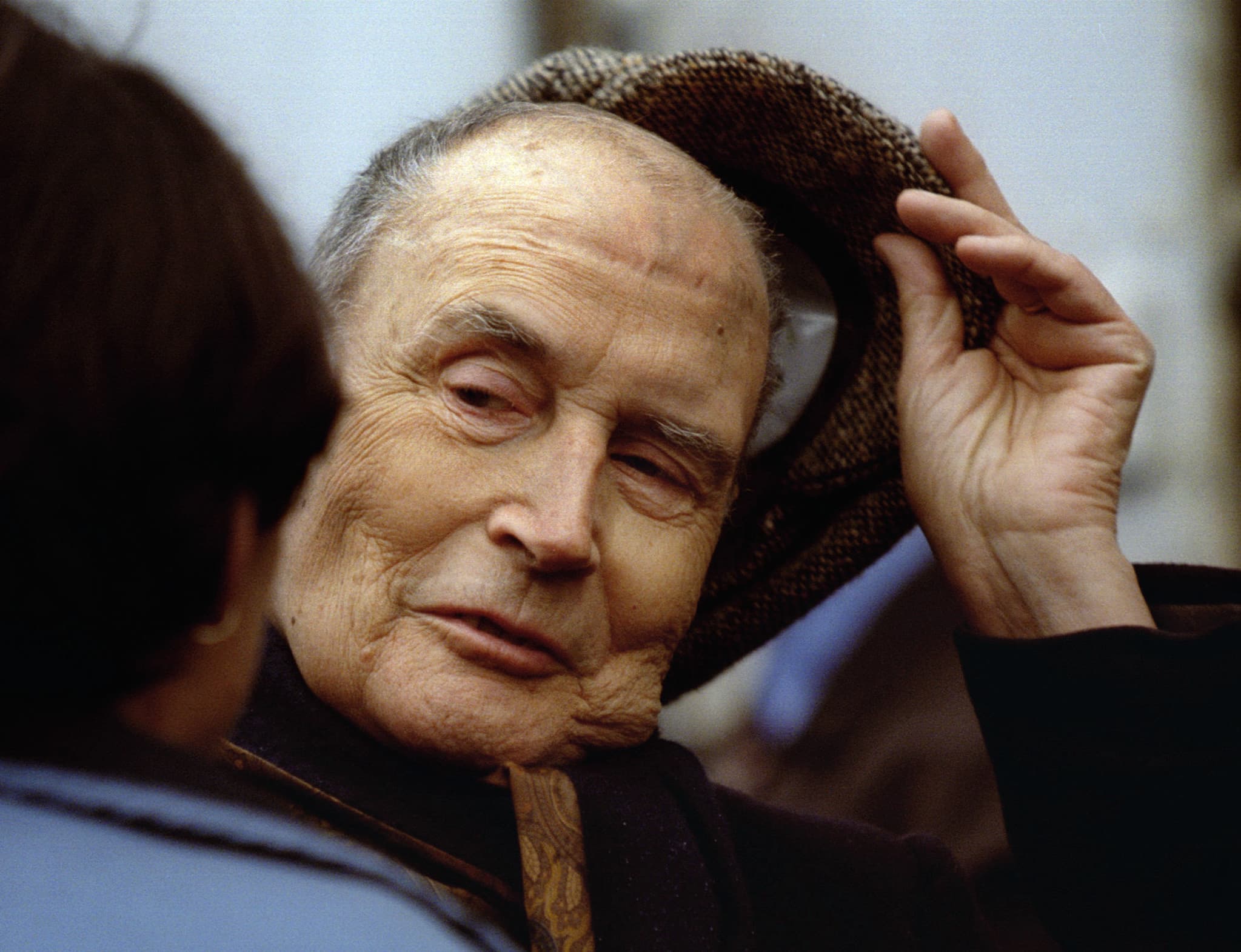 French President Francois Mitterrand raises his cap as he goes for a walk in the streets of Chateau-Chinon in 1995.