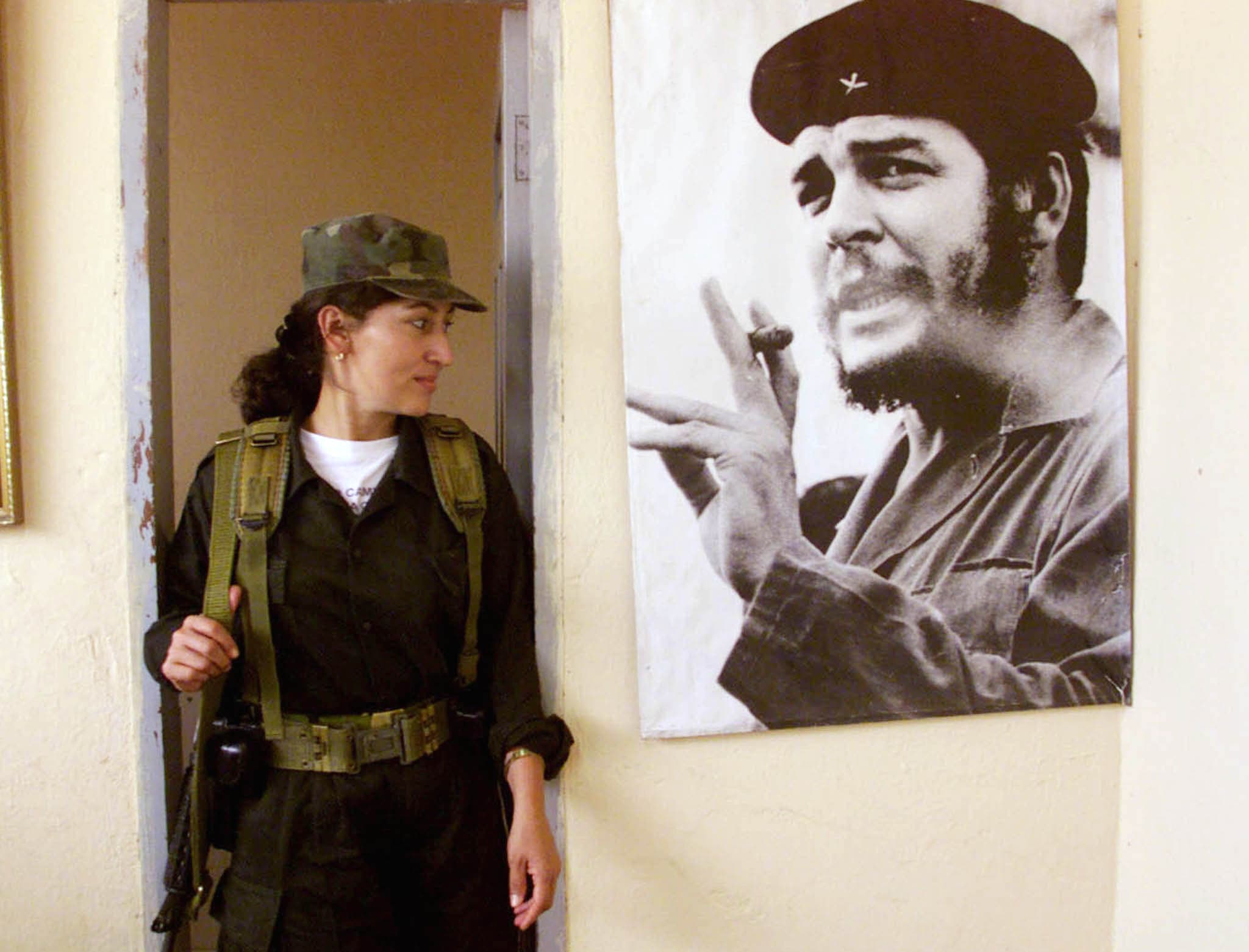 A Colombian female leftist rebel looks at the photo of legendary guerrilla leader Ernesto "Che" Guevara in a temporary rebel headquarters in San Vicente del Caguan in 1999.