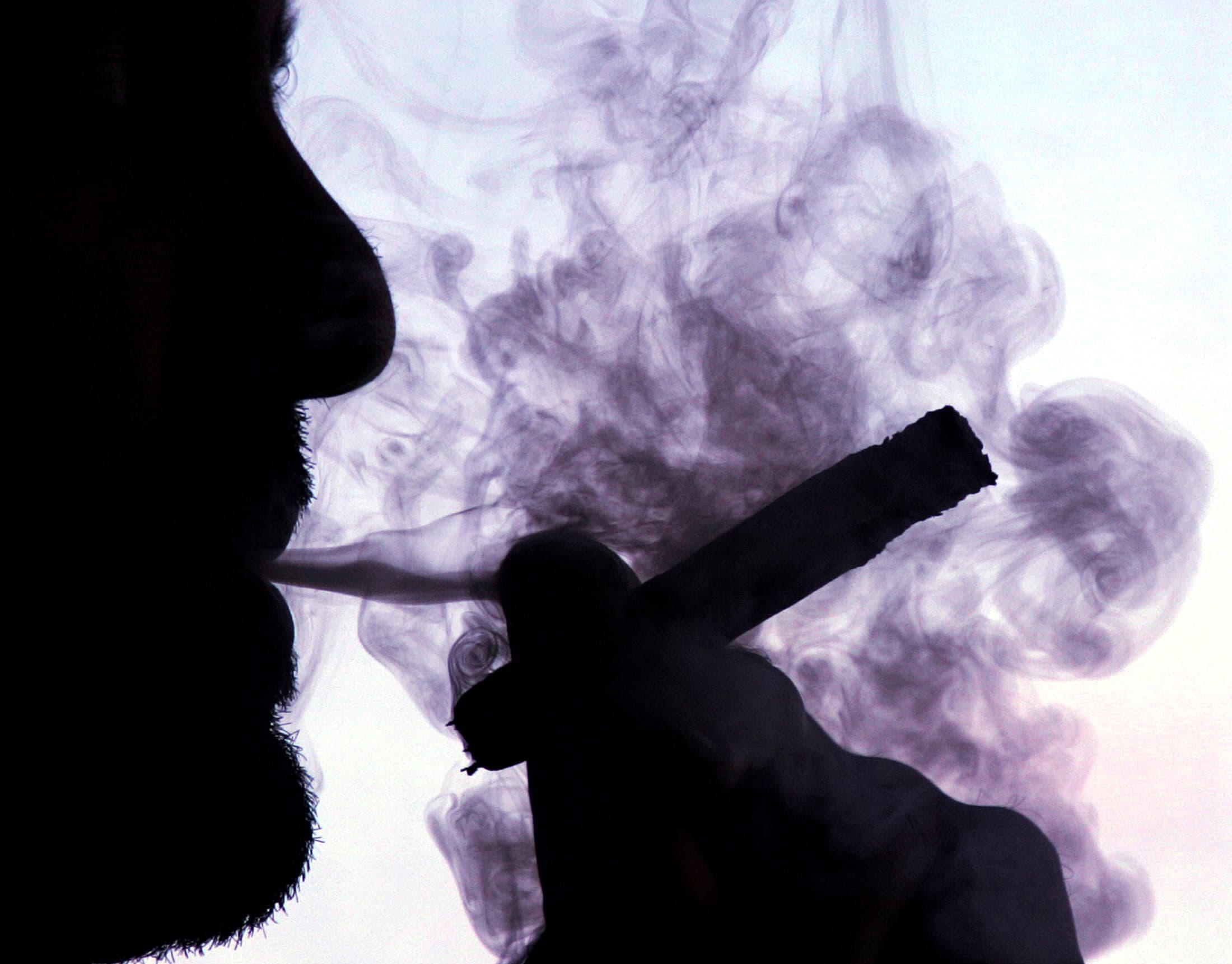 A man smokes a cigar while standing next to a window in Havana, January 20, 2005.