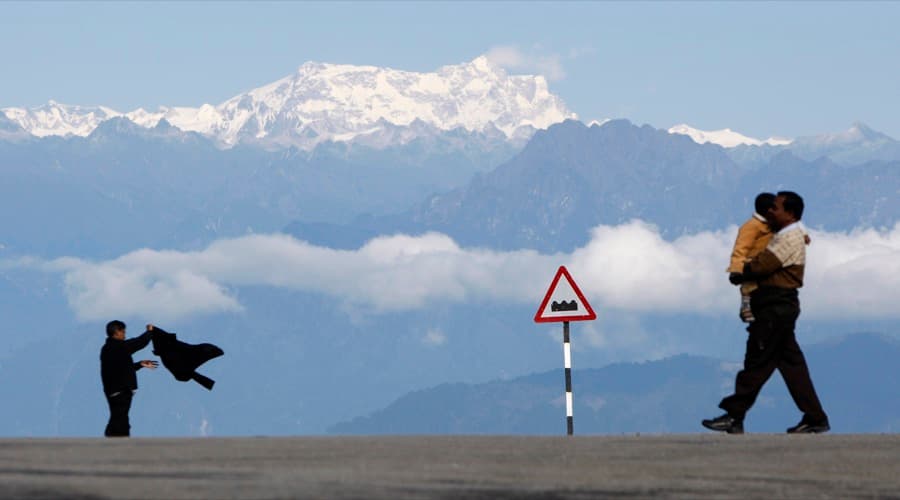 A man with a child walks in front of the Gankar Punsun glacier at Dochula in Bhutan.