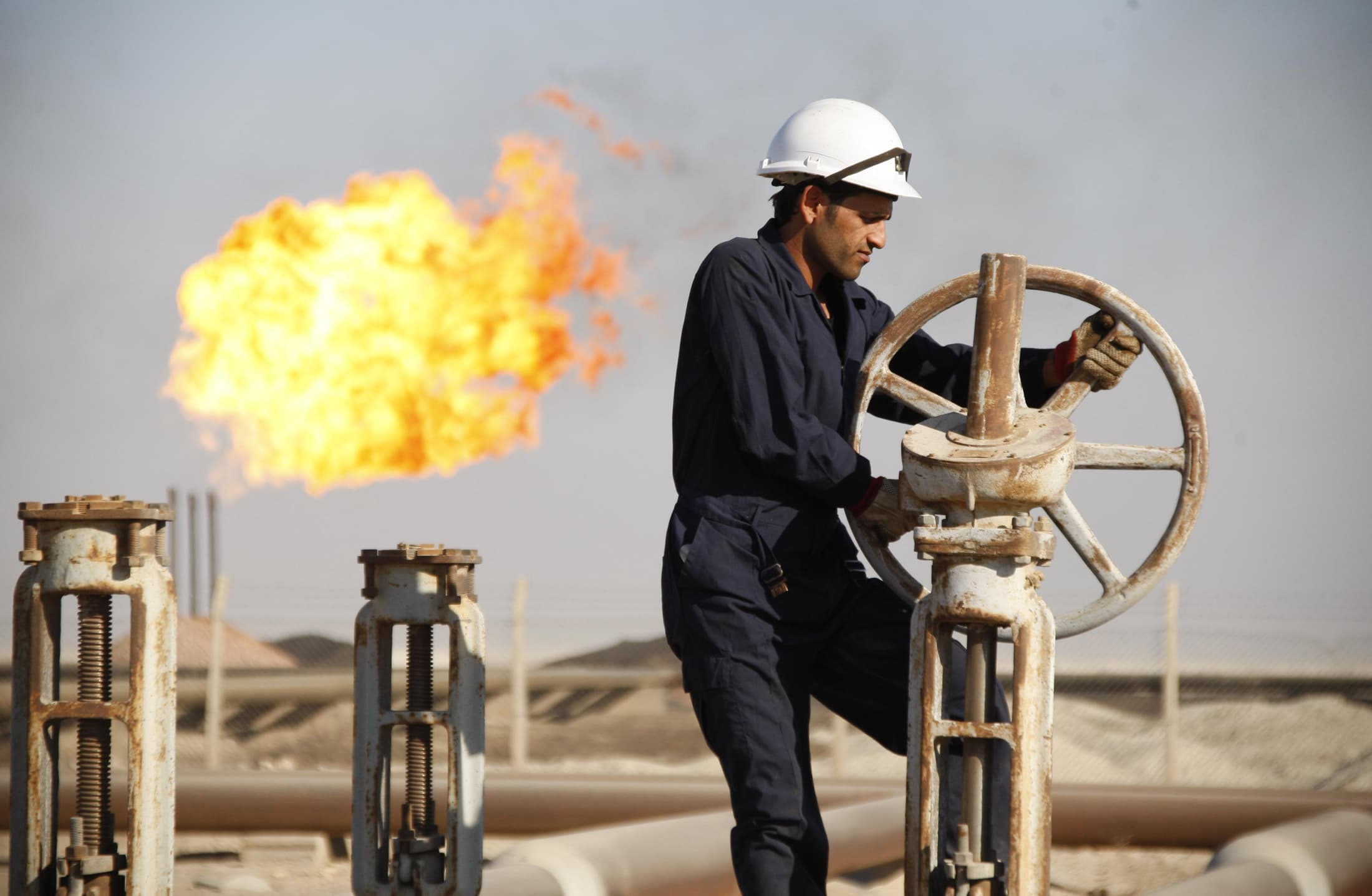 A worker adjusts the valve of an oil pipe at West Qurna oilfield in Iraq's southern province of Basra