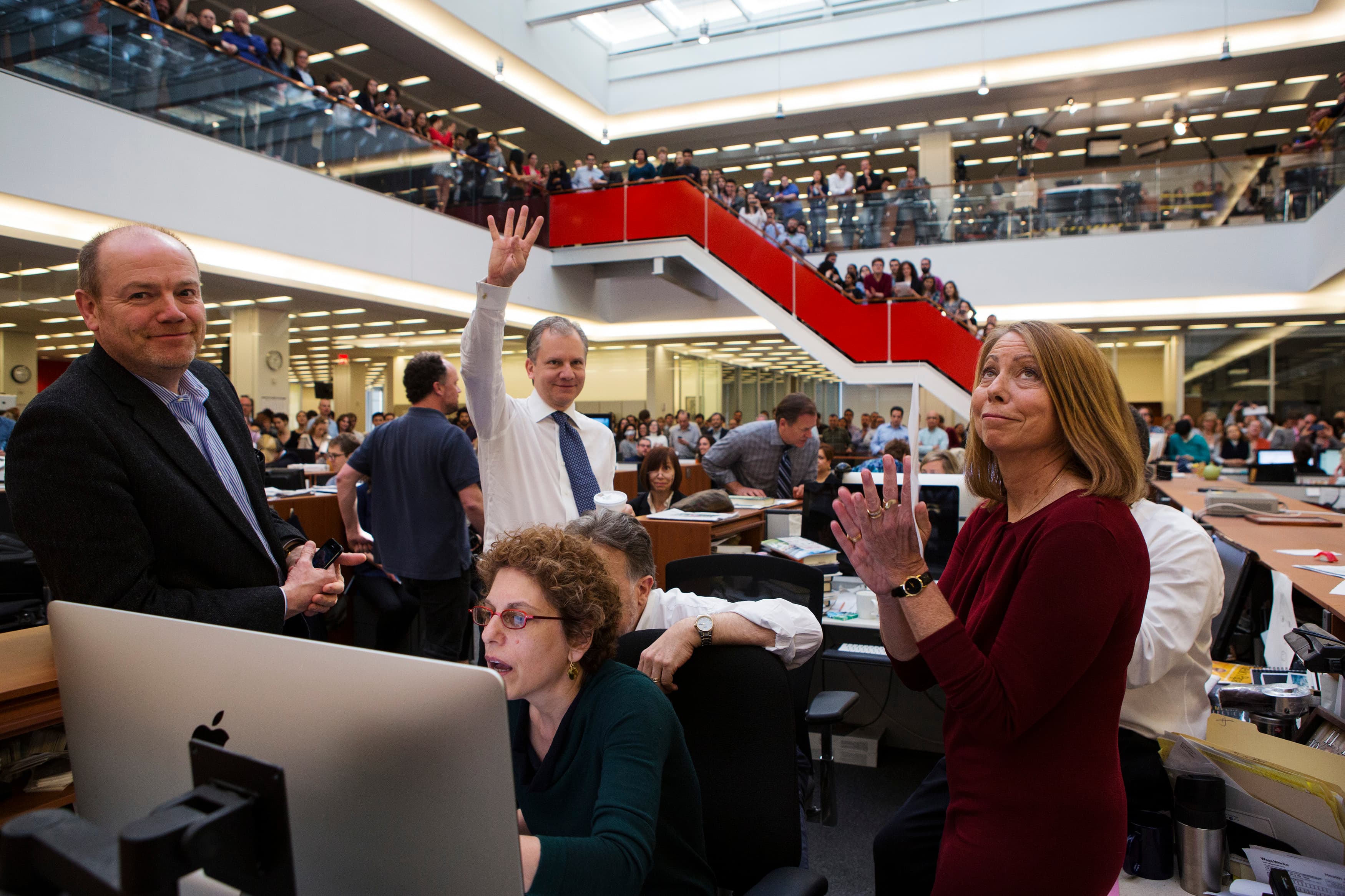 Publisher Arthur Sulzberger Jr. holds up four fingers to indicate the four Pulitzer Prizes won by the New York Times in 2013 as Executive Editor Jill Abramson looks on.