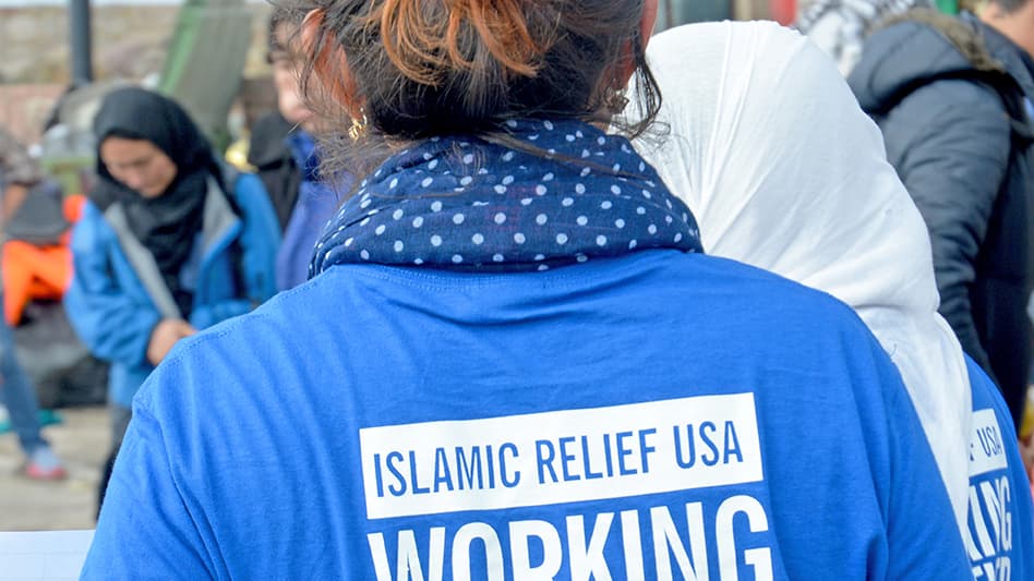 A relief worker walks among refugees in Lesbos