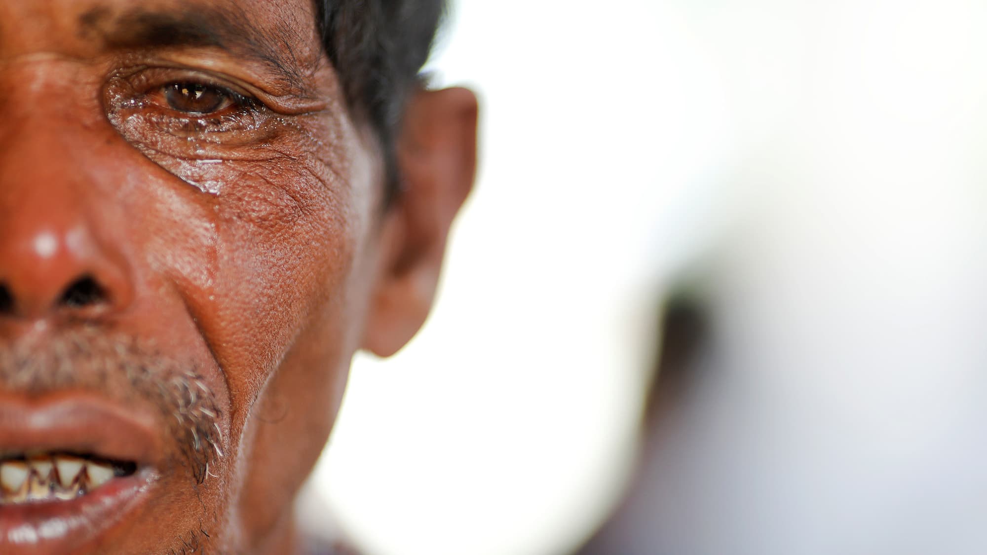 A close-up photograph of Lalu Miya who is crying over the bodies of his wife and children.