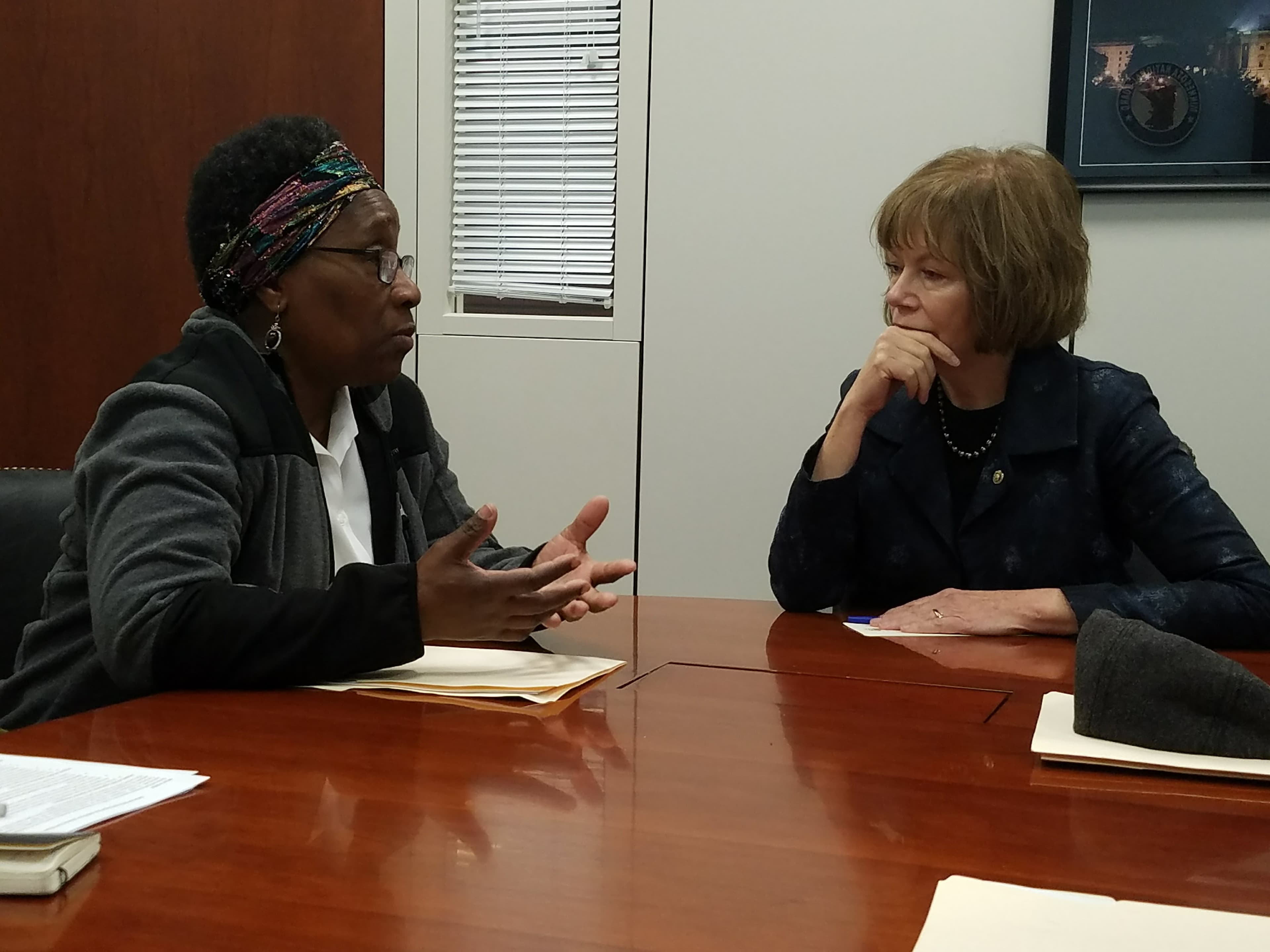 Woman at table talks to another woman