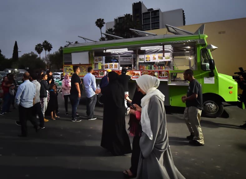Members of the Islamic Center of Santa Ana lineup after sunset in front of a taco truck.