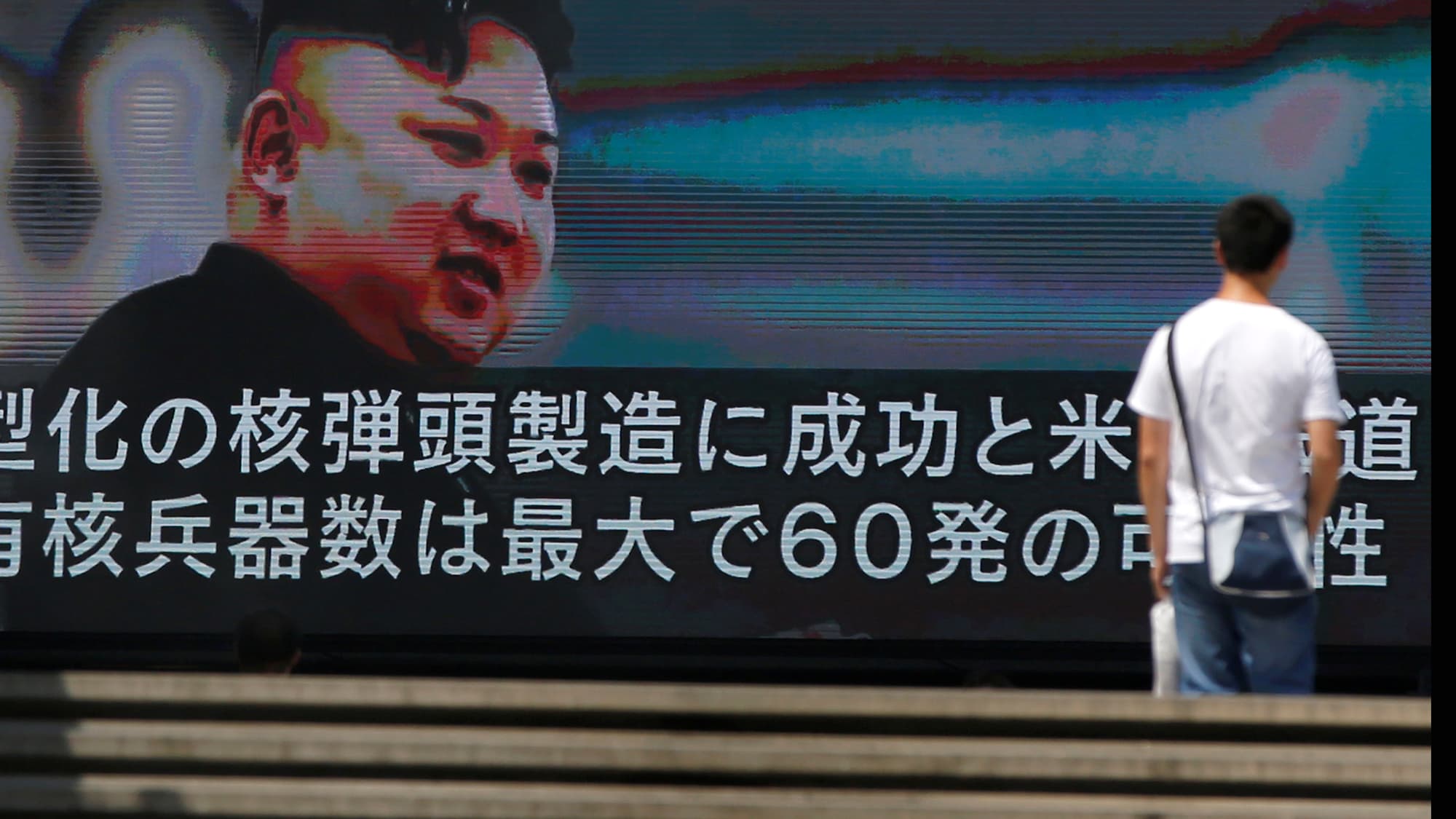 A passerby walks past a street monitor showing news of North Korea's fresh threat in Tokyo, Japan.