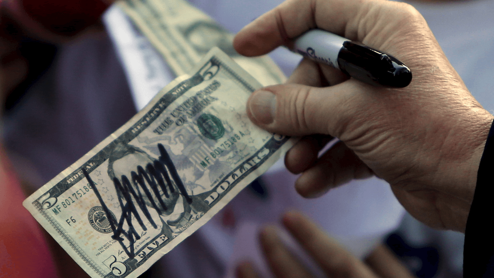 Donald Trump hands a five-dollar bill back to a supporter after signing it for her following a rally with sportsmen in Walterboro, South Carolina, Feb. 17, 2016.