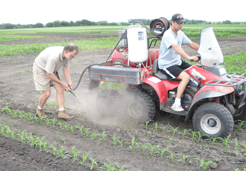 Jim Eklund and Frank Forcella conduct an early test of the concept with a single-nozzle blaster. Jim is driving the ATV and Frank is applying the grit.