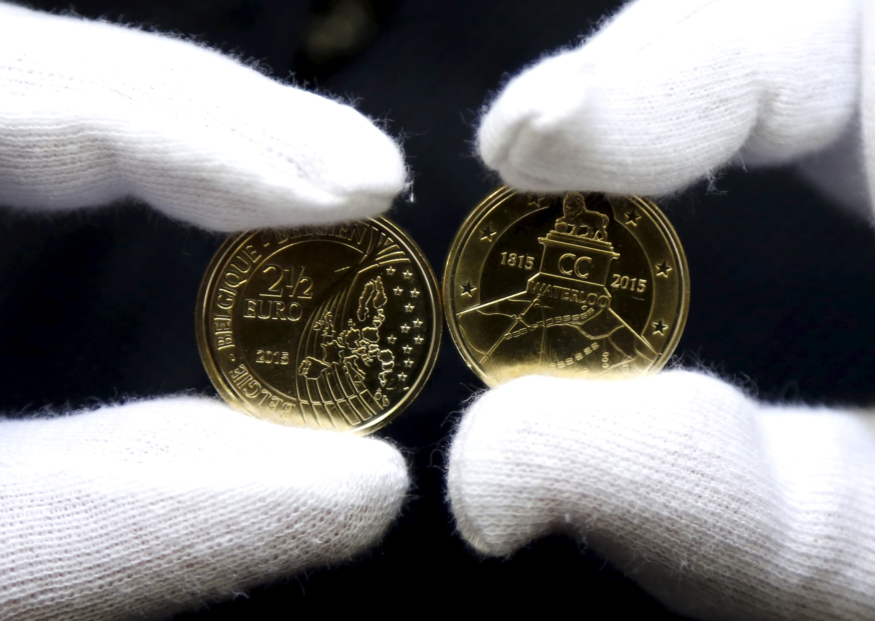 A worker displays newly minted commemorative 2.5 euro coins to mark the bicentennial of the battle of Waterloo.