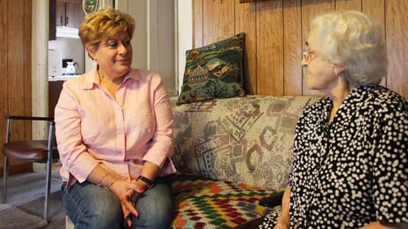 Lucy Oliveira of the New Bedford Immigrants' Assistance Center sits with 86-year-old Margarida Xavier, who moved to the US from Portugal in the 1960s. Oliveira visits Xavier's home every month and often helps Xavier read her mail.