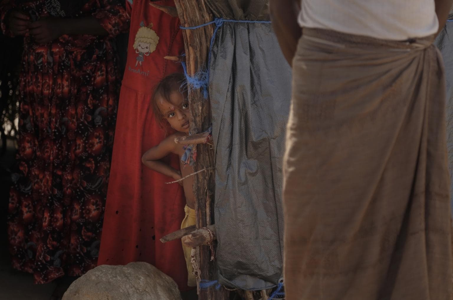 A young boy peaks from behind his tent at a camp for displaced people in Hajjah, Yemen. He and his family have been forced from their homes twice because of airstrikes in the nine months that a coalition led by Saudi Arabia, and supported by the United St