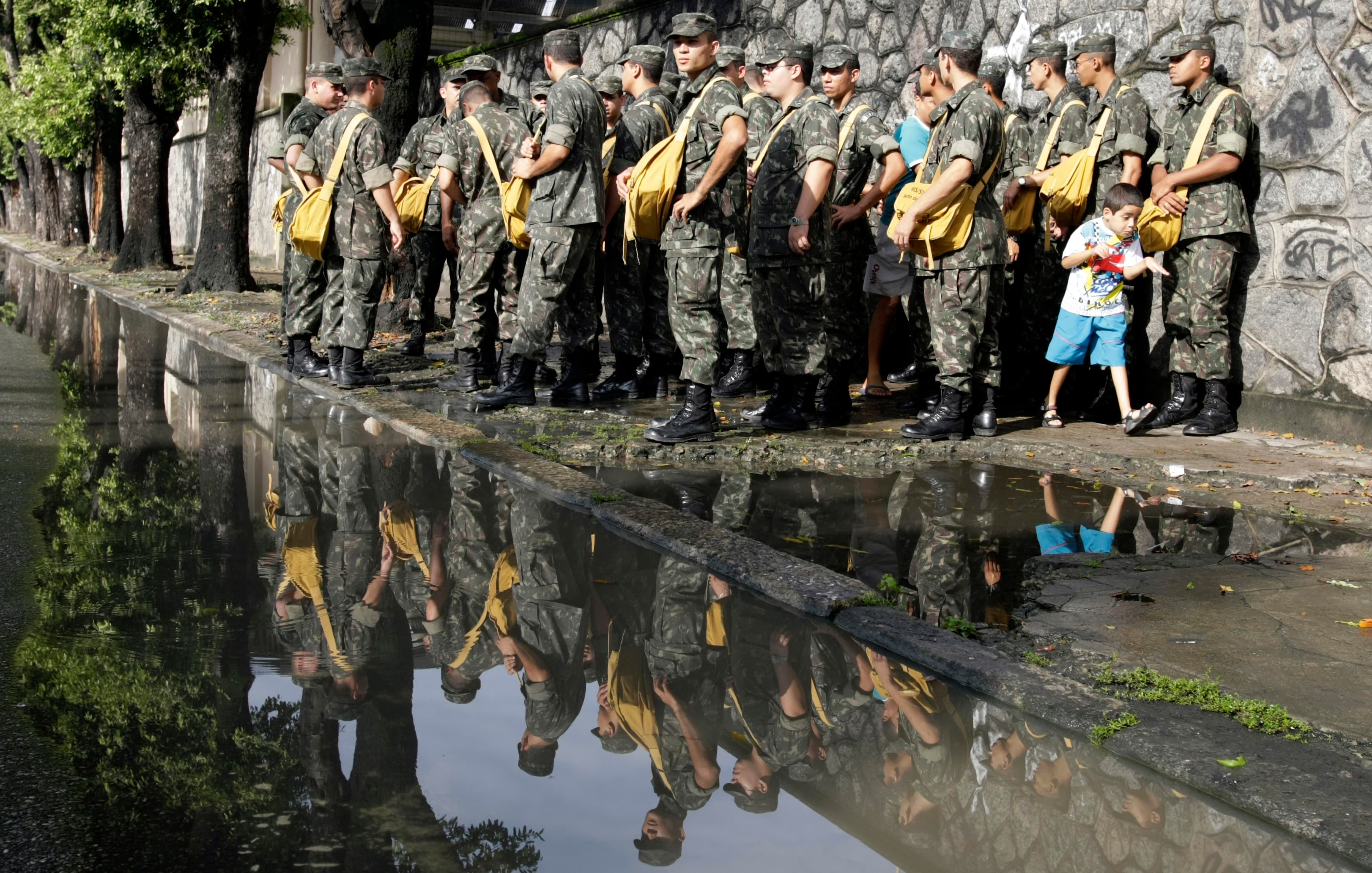 A boy walks near Brazilian soldiers before they carry out an inspection for Aedes mosquitoes at the Realengo neighborhood in Rio de Janeiro April 8, 2008. Dengue, a viral disease spread by the Aedes mosquito, has killed 67 people since January and infecte