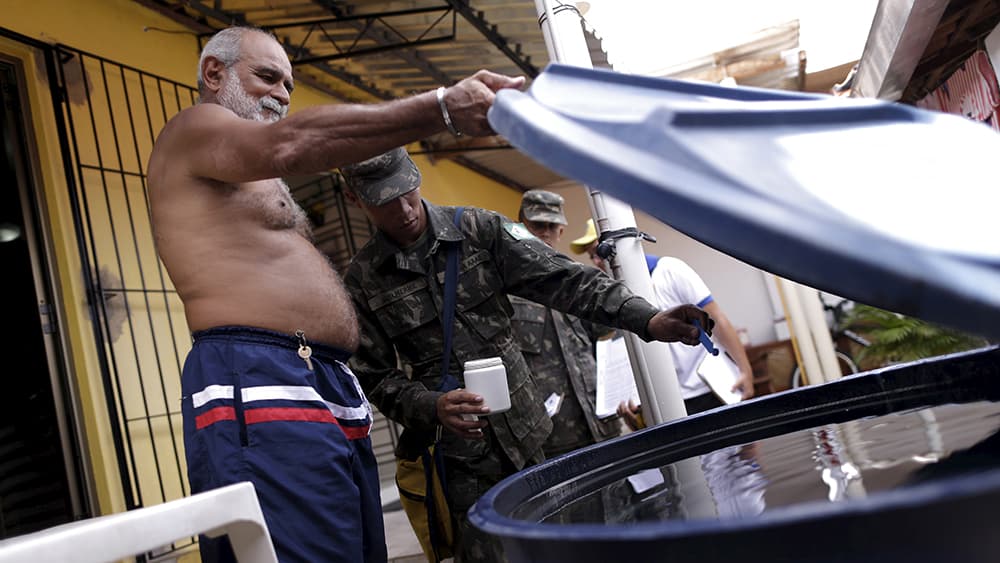 Brazilian soldiers inspecting water container for Zika