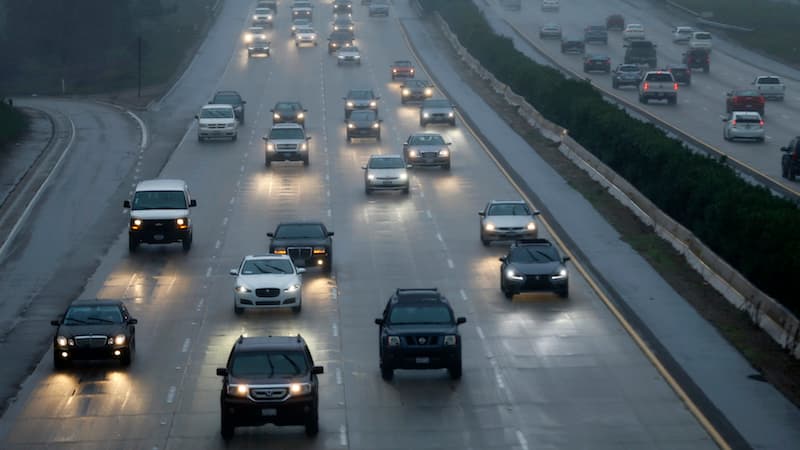 Cars move in the rain along a highway