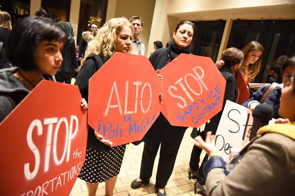 Protestors hold up signs in the shape of stop signs and call for the end of immigration detentions