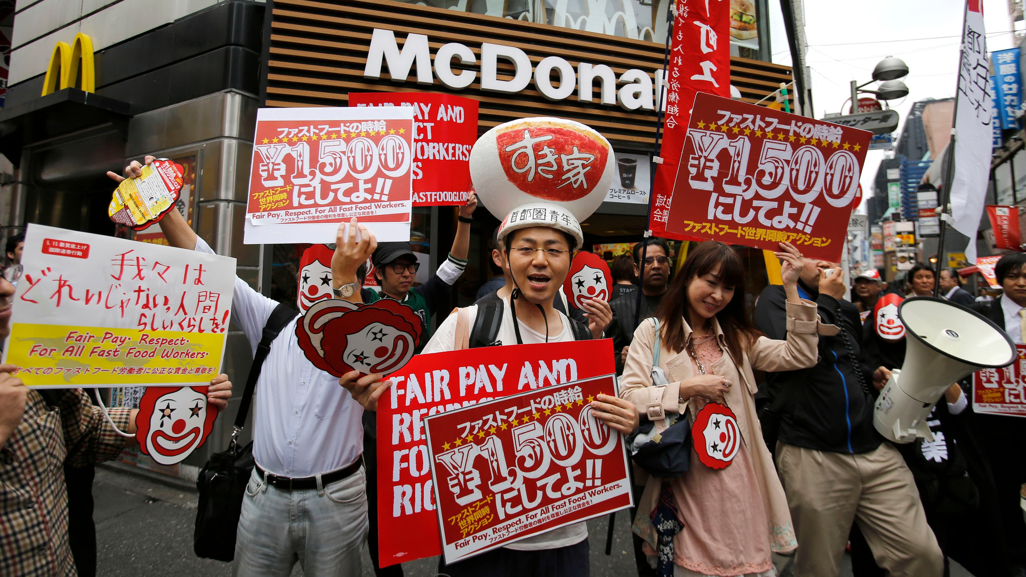 Demonstrators holding posters march during a protest to demand higher wages for fast-food workers in front of a McDonald's fast-food restaurant in Tokyo's Shibuya shopping and amusement district May 15, 2014.