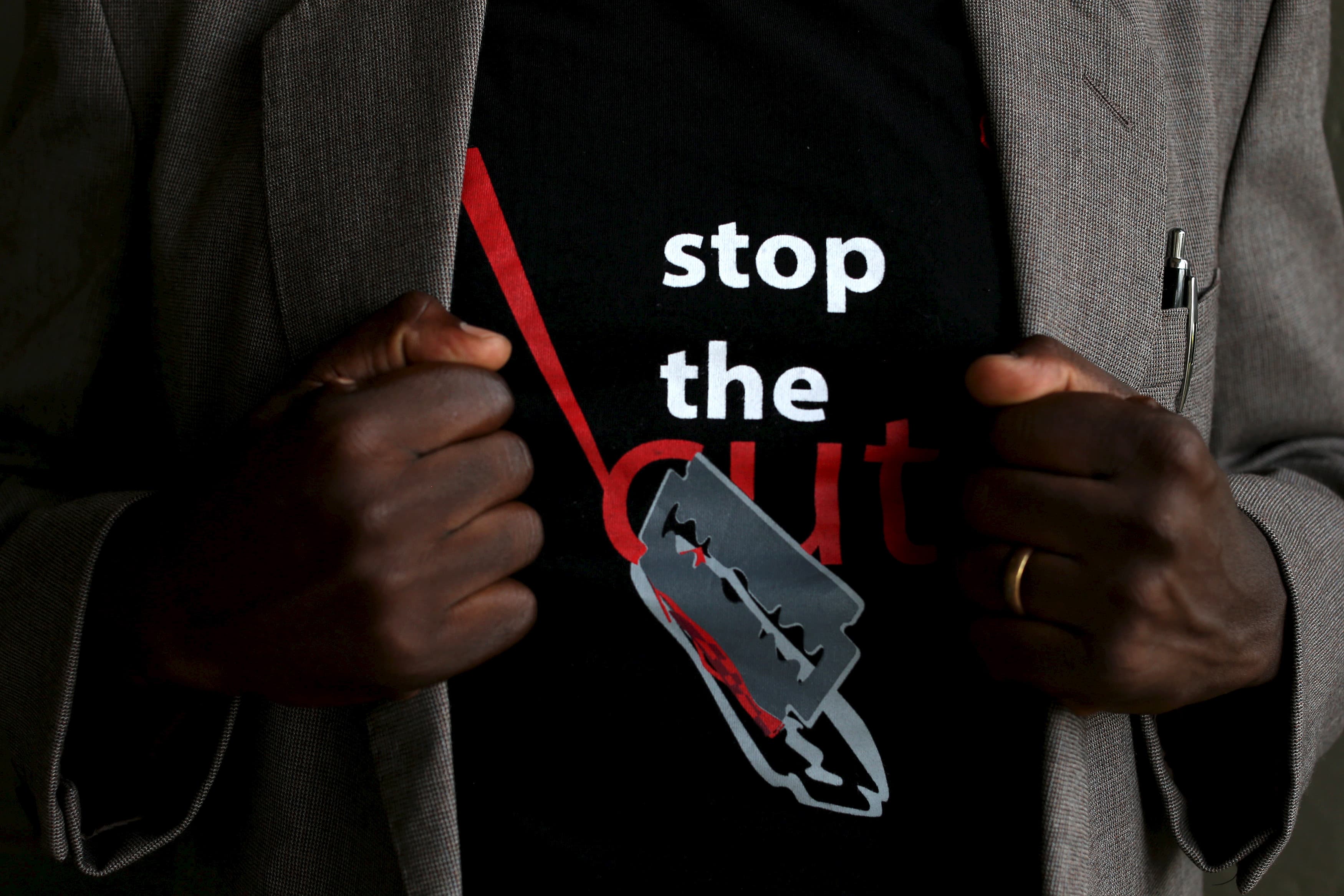 A man shows the logo of a T-shirt that reads "Stop the Cut"