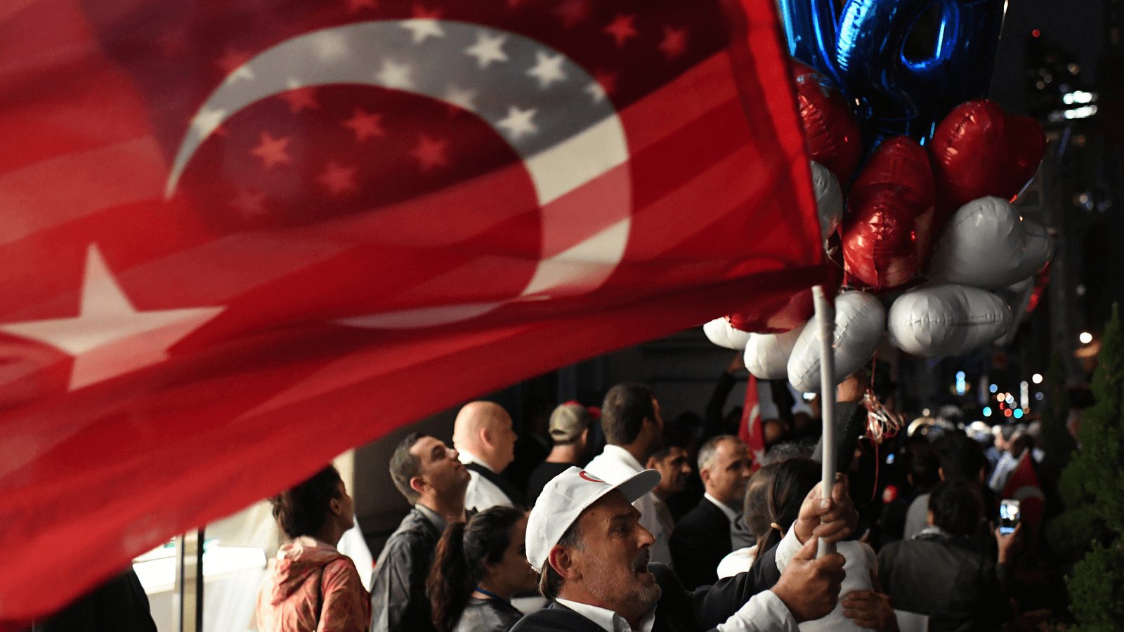 A supporter of Turkish President Tayyip Erdogan waves a US and Turkish flag as he waits for him to arrive outside of The Peninsula hotel in Manhattan, New York City, Sept. 19, 2017.