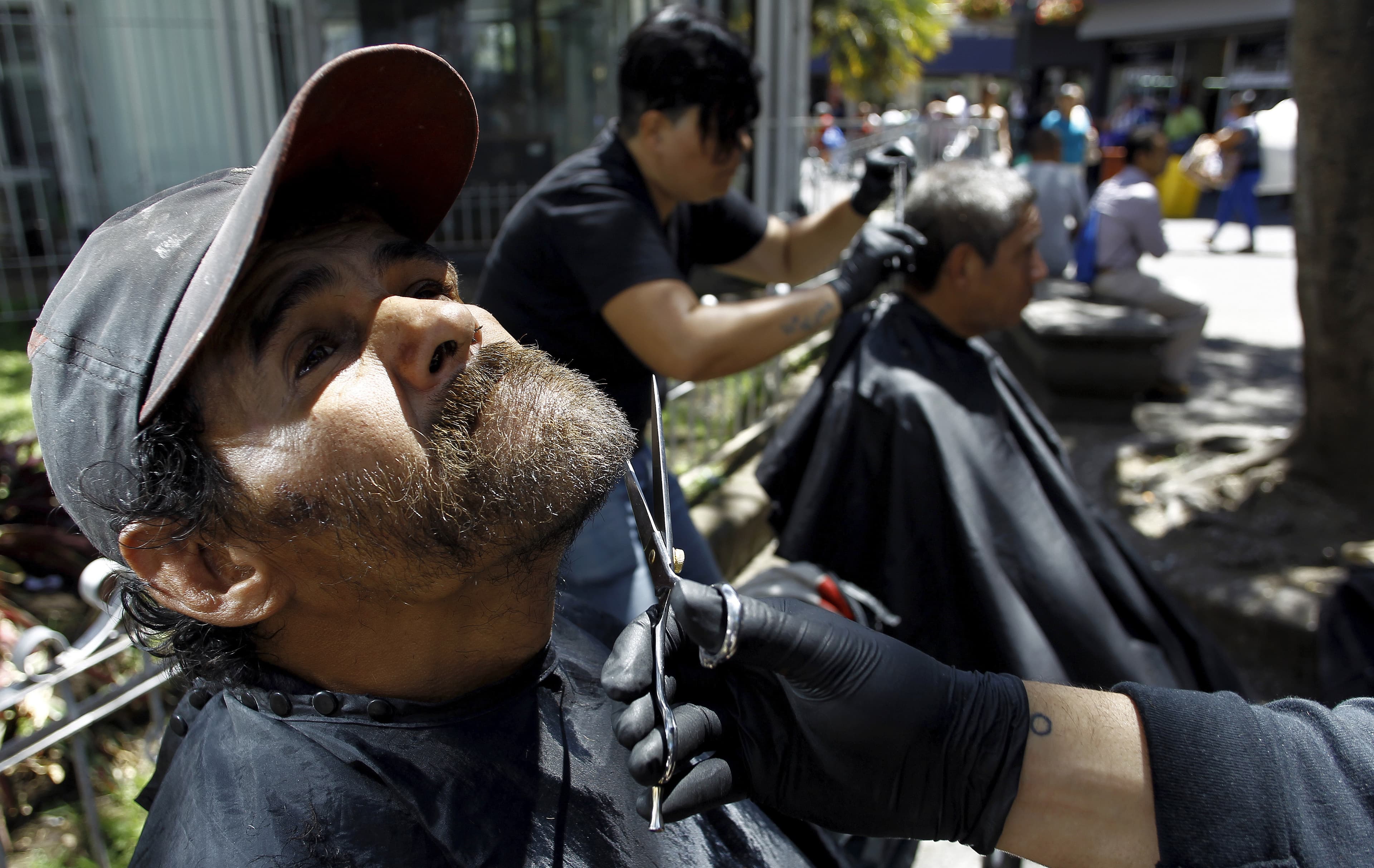 A volunteer from the social work community "Friends of the World" trims the beard of a homeless man in San Jose, Costa Rica February 24, 2016.