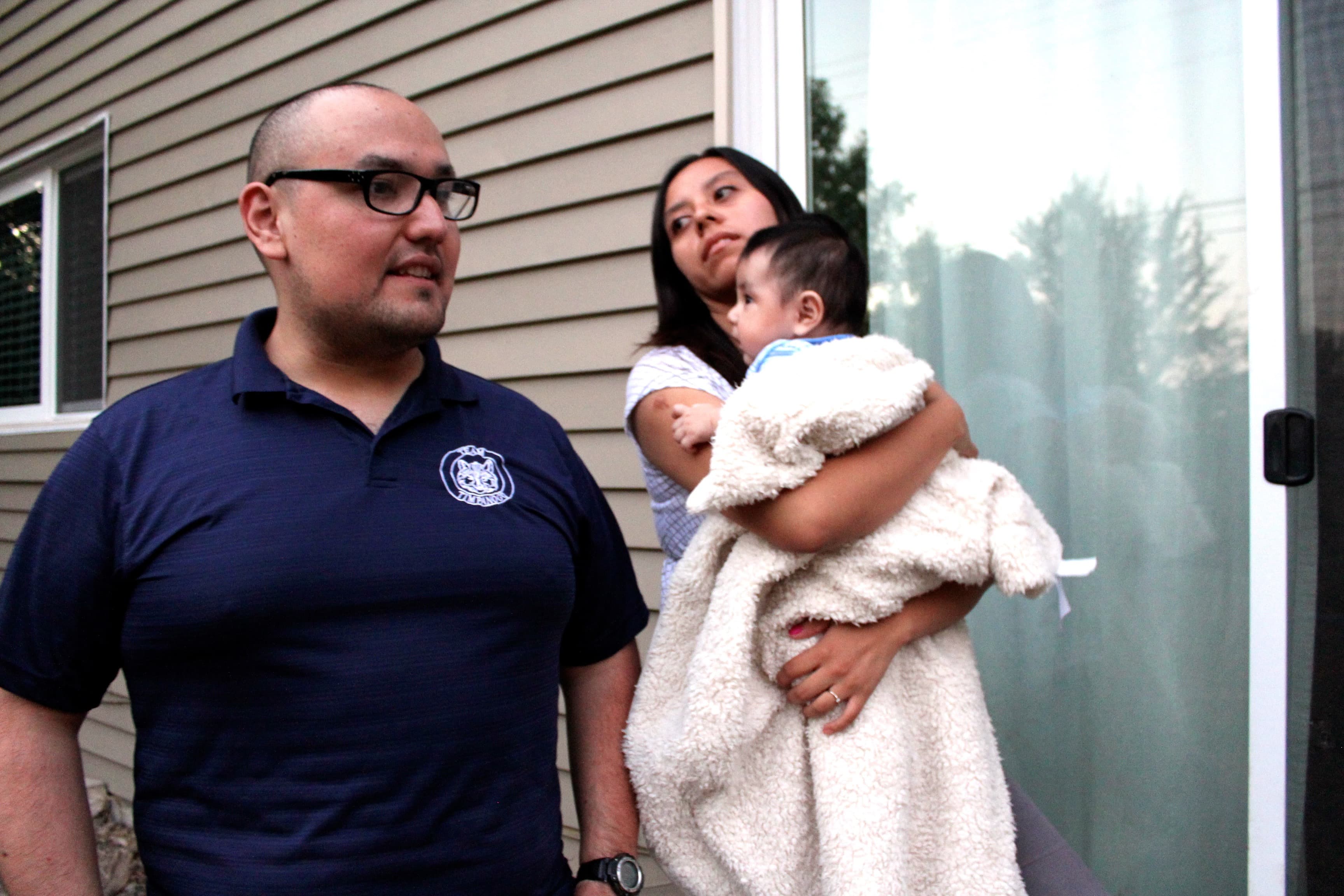 Man and woman with baby in front of house