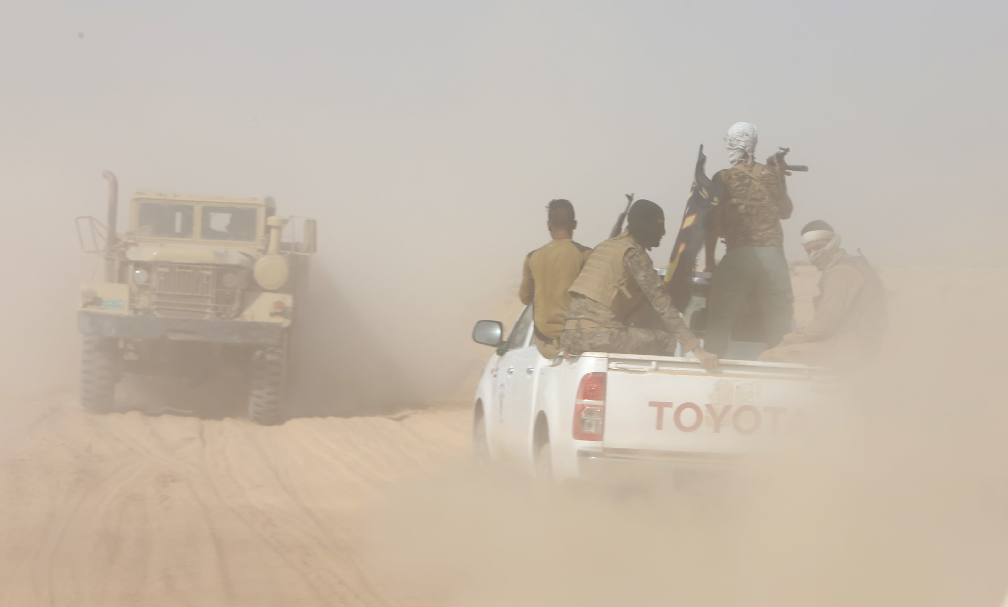 Iraqi army personnel ride on military vehicles