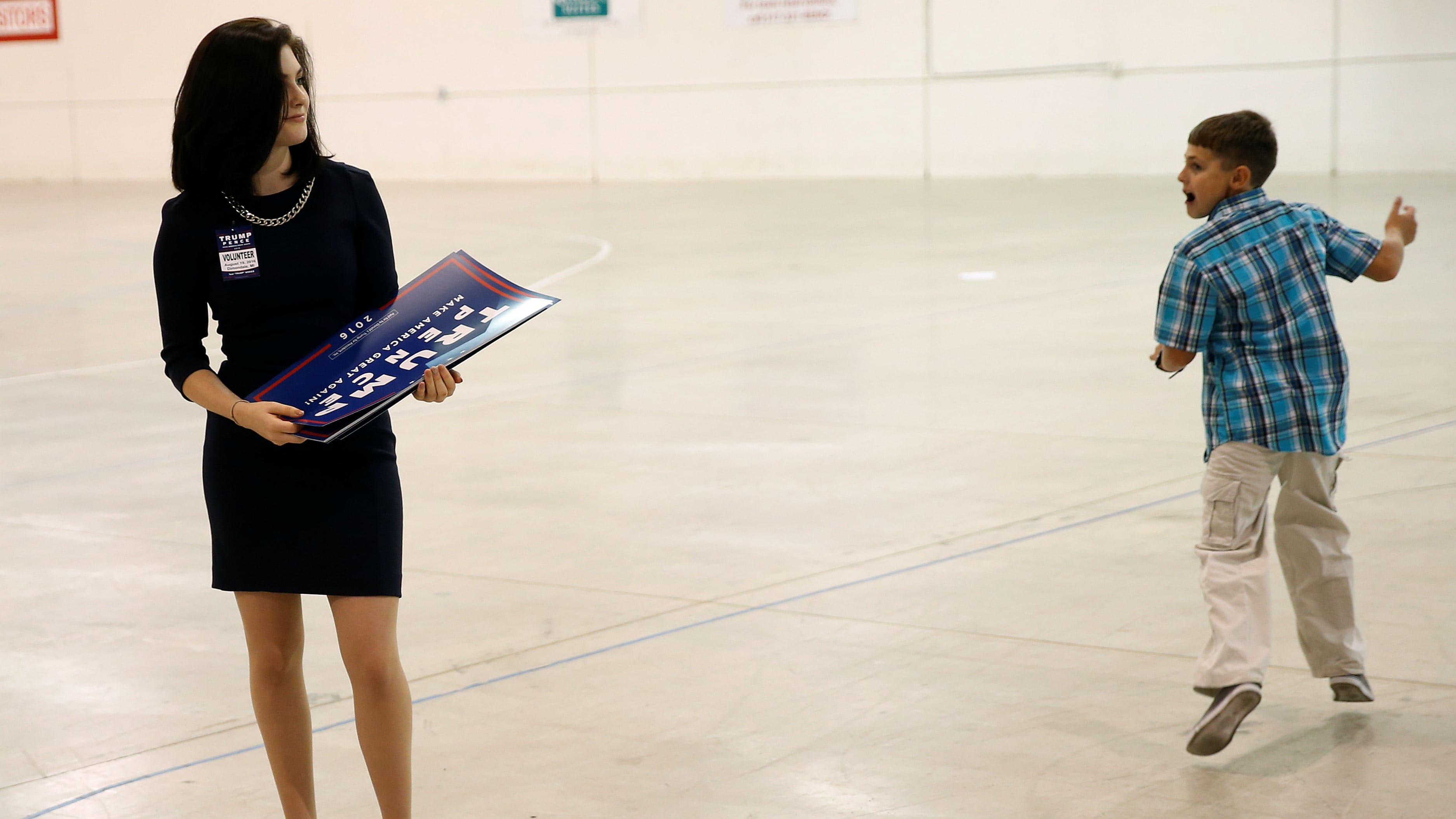 A youth runs past a volunteer for Republican presidential nominee Donald Trump.