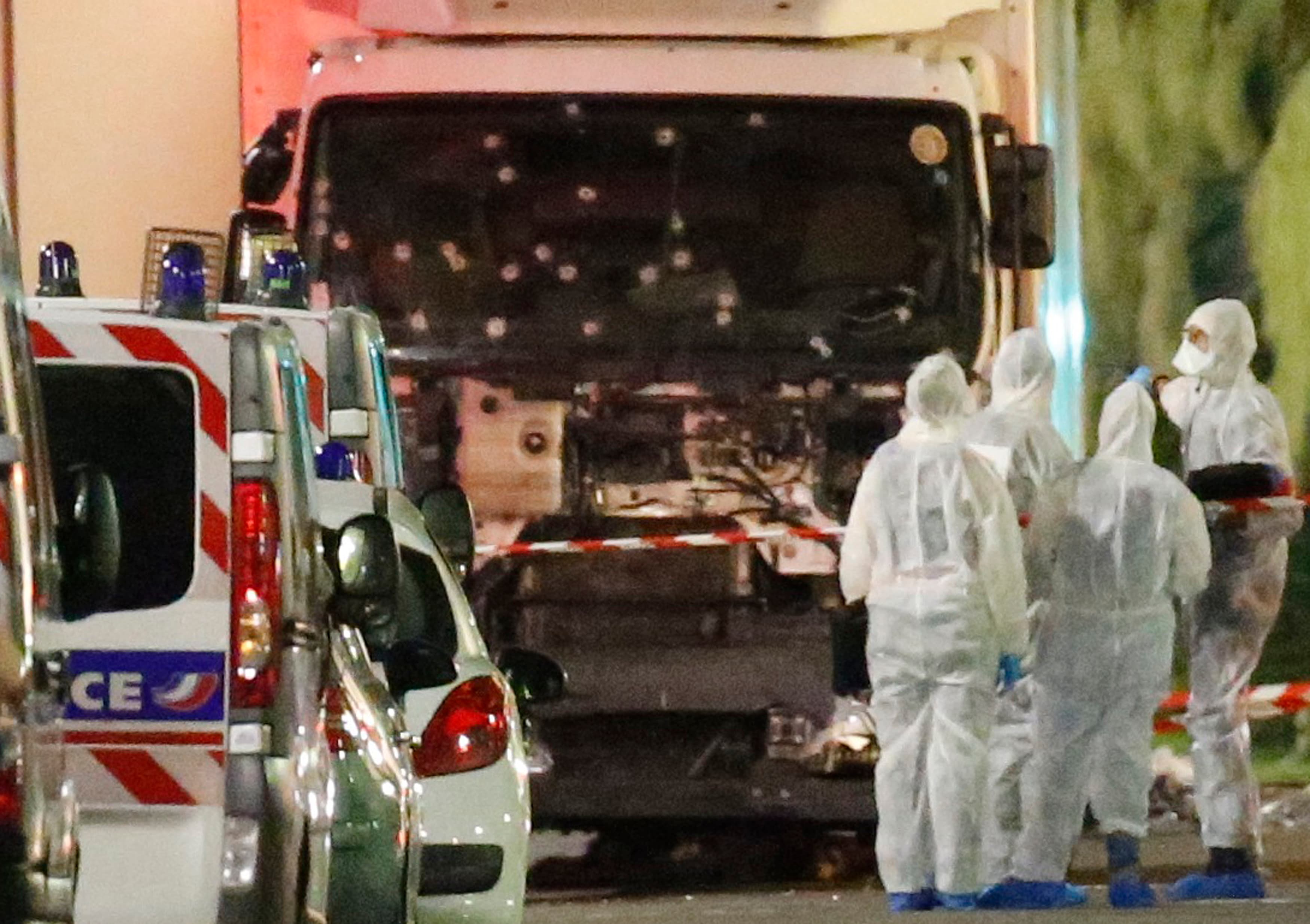 French police forces and forensic officers stand next to a truck