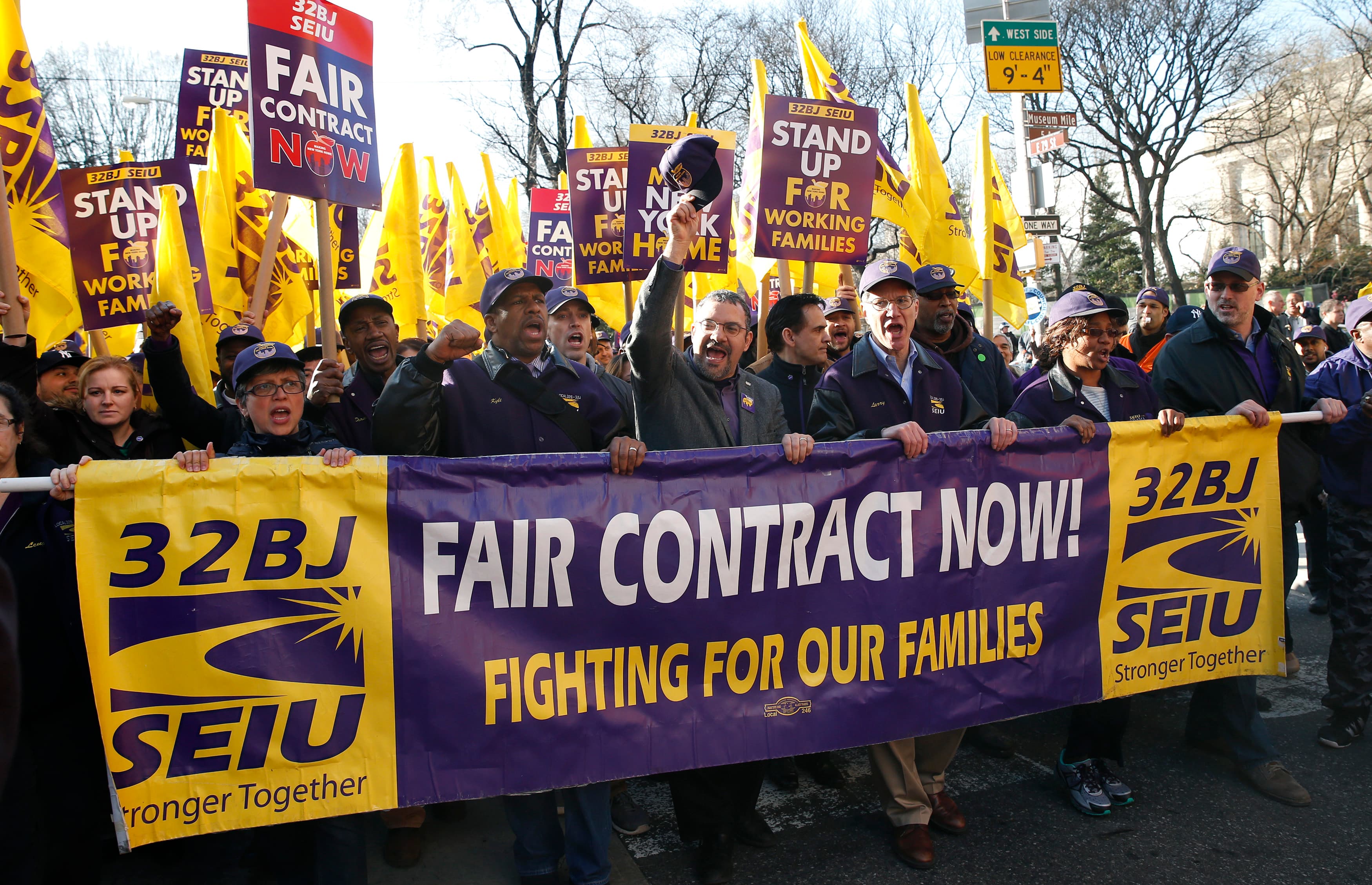 Hector Figueroa (center raising hat), president local chapter 32BJ of the Service Employees International Union, leads a march