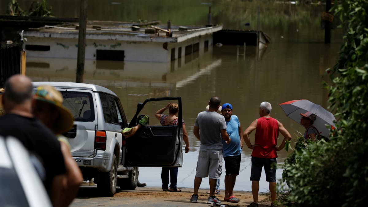 Local residents look at the flooded houses close to the dam of the Guajataca lake, on September 23, 2017.