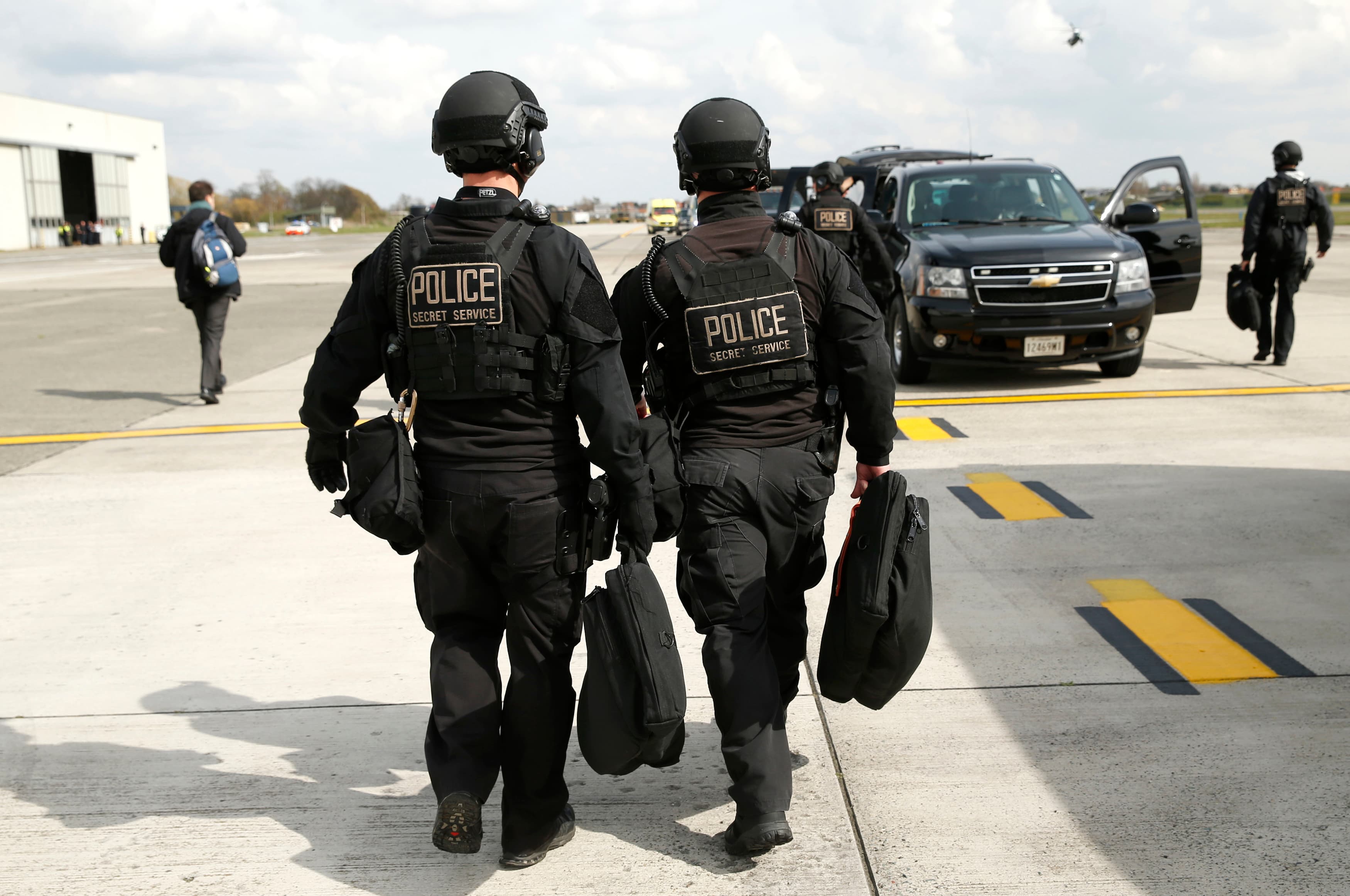 Two Secret Service CAT team members walk toward their motorcade vehicle at Brussels Airport in Belgium March 26, 2014.Three members of the U.S. Secret Service detail that protects U.S. President Barack Obama were sent home from Amsterdam for disciplinary