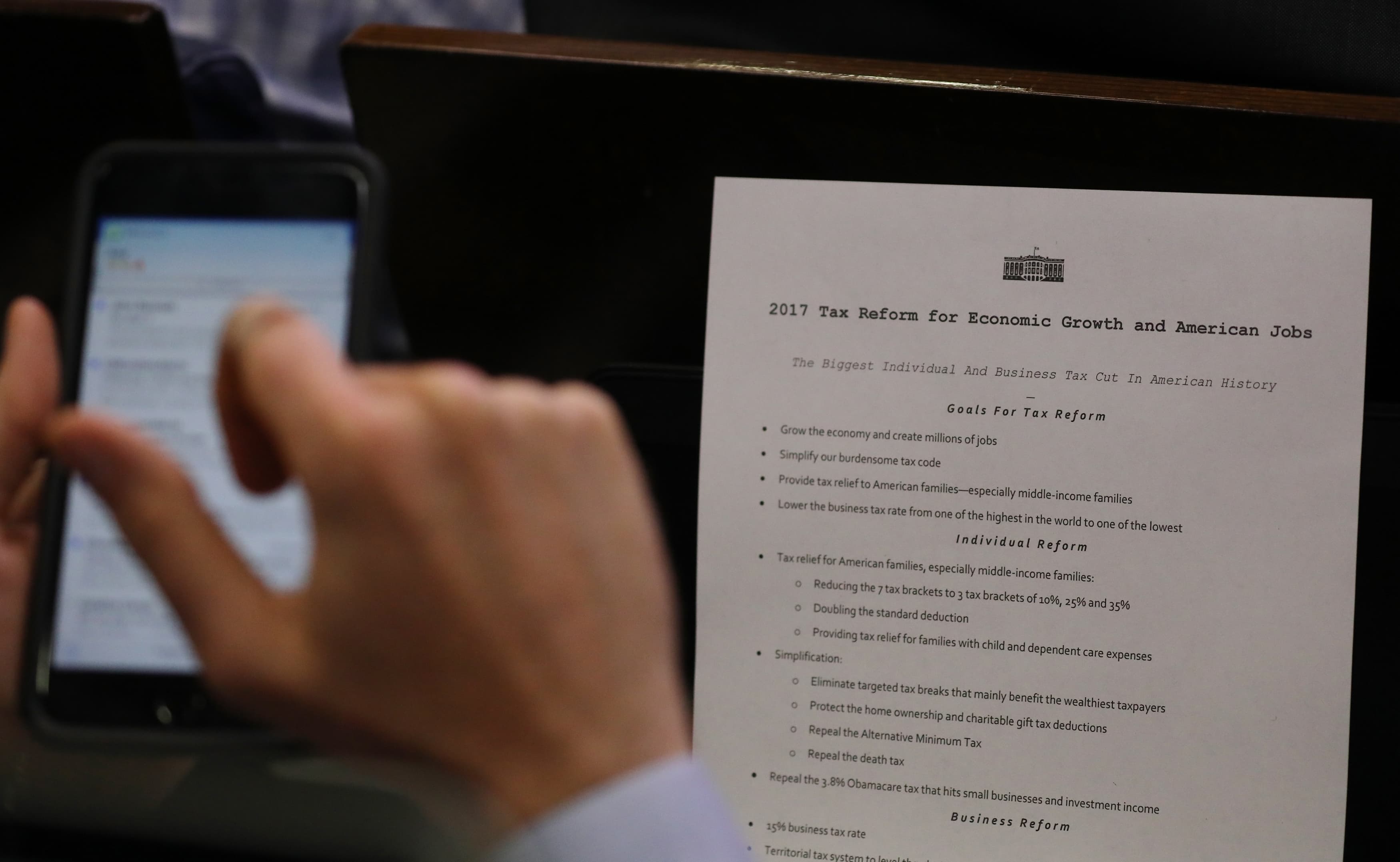 A reporter shoots a picture of a White House press release on its tax reform plan during the daily briefing at the White House in Washington, April 26, 2017.